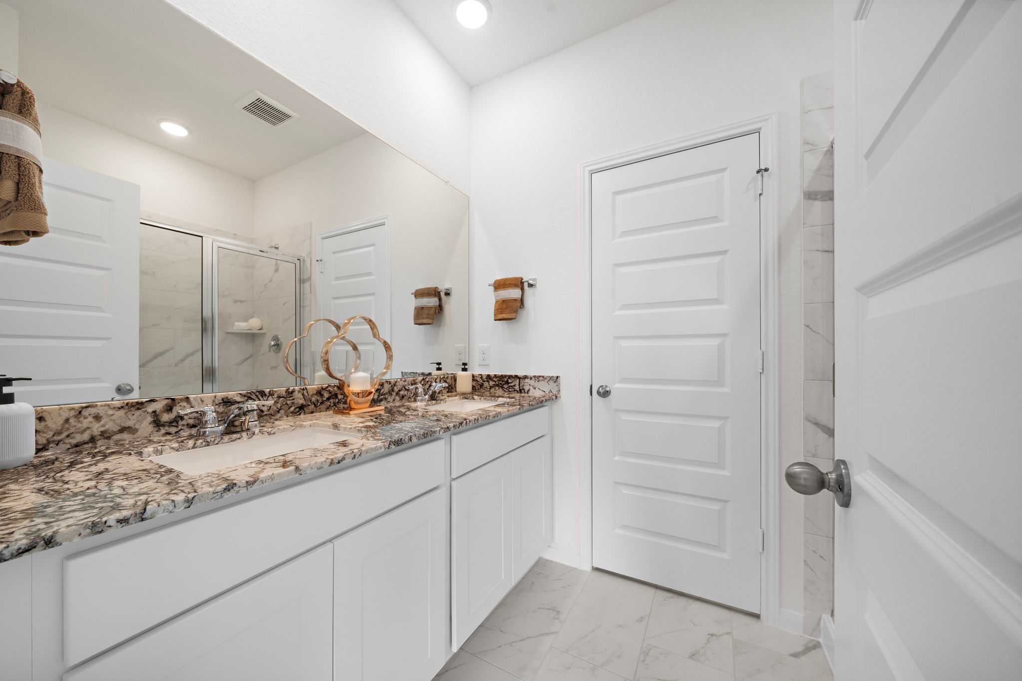 Spacious primary bathroom at The Villages at WestPointe in Dayton Texas with double vanity granite counters and frameless glass shower