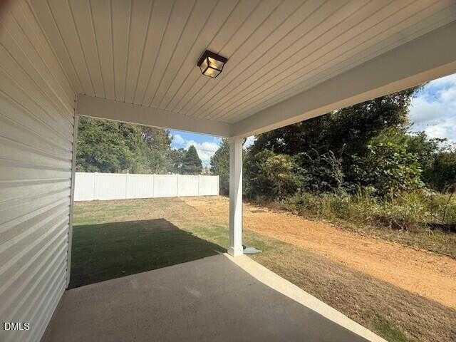 Covered back porch with wooden ceiling and lantern light overlooking fenced backyard in Davidson Homes The Preston C, Gregory Village, Lillington, NC