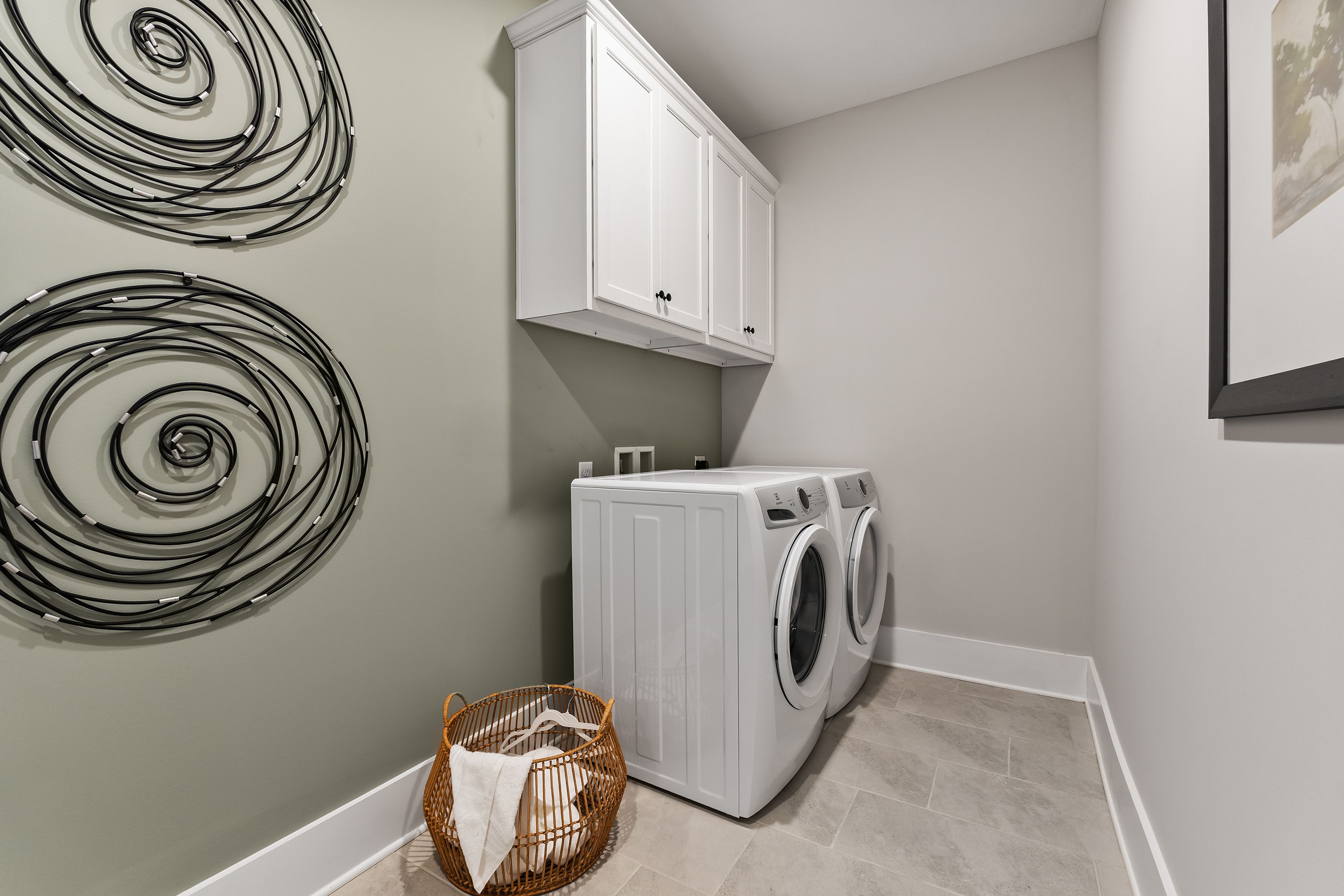 Modern laundry room at River Road Estates in Decatur Alabama with white washer dryer, cabinets, and abstract wall art