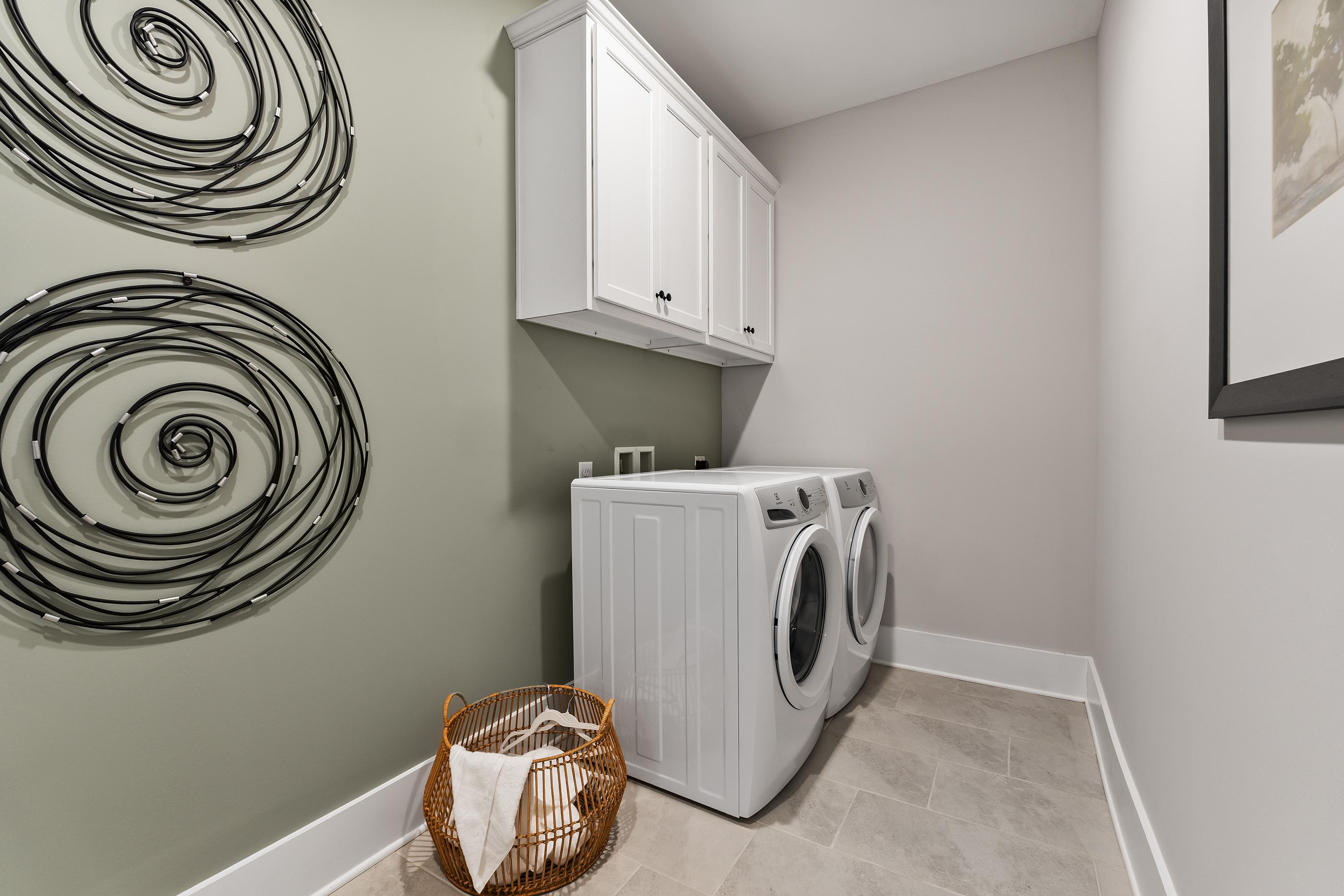 Modern laundry room at River Road Estates in Decatur Alabama with white washer dryer, cabinets, and abstract wall art