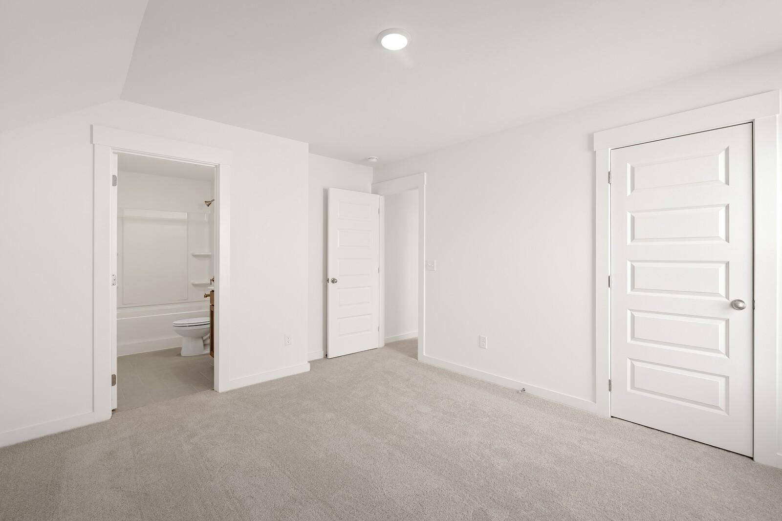 Spacious secondary bedroom with attached full bath, white walls, and carpet flooring in Davidson Homes The Ash C, Mt. Juliet