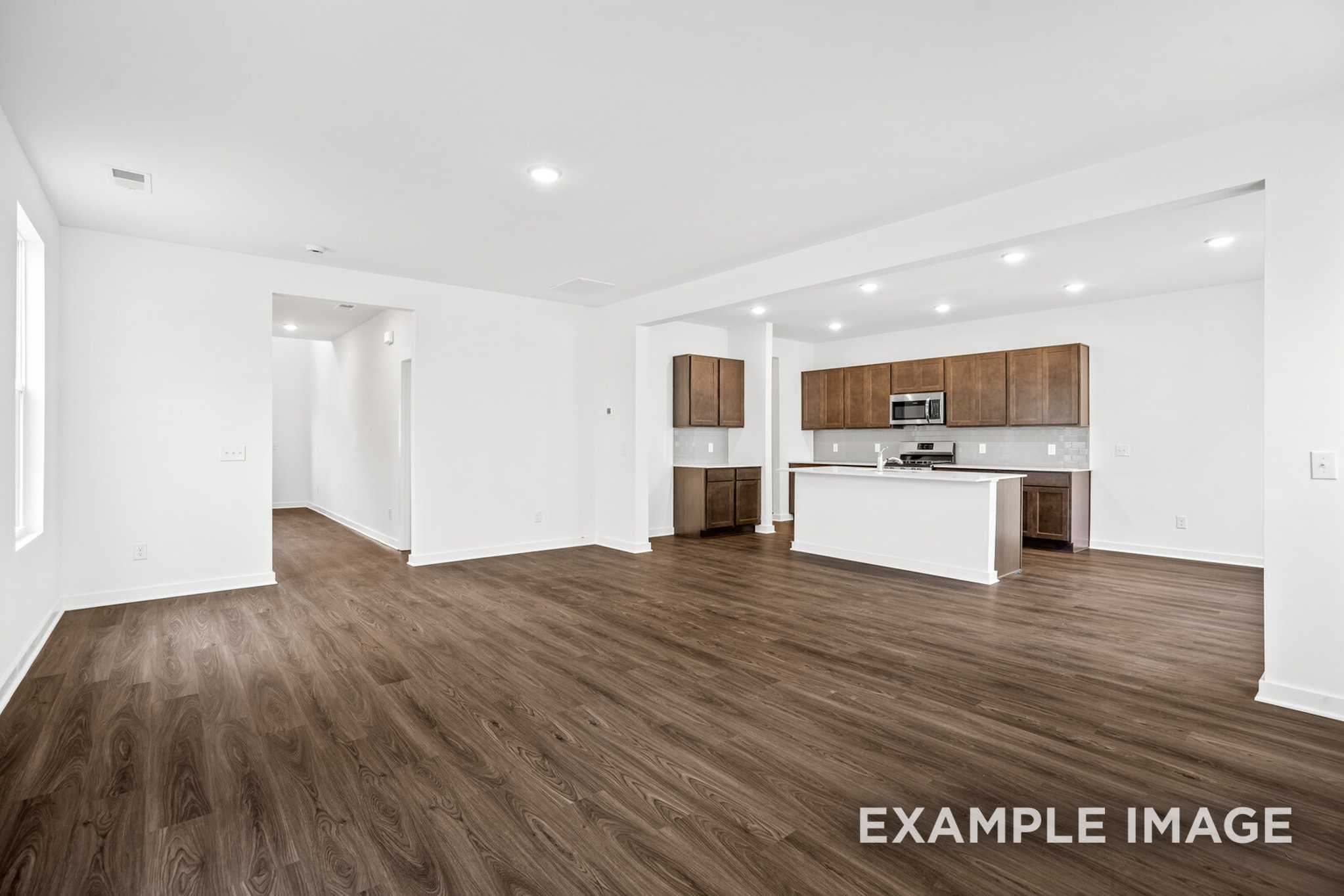 Open-concept kitchen and living area in Grayson C with white cabinets, large island, hardwood floors, and recessed lighting