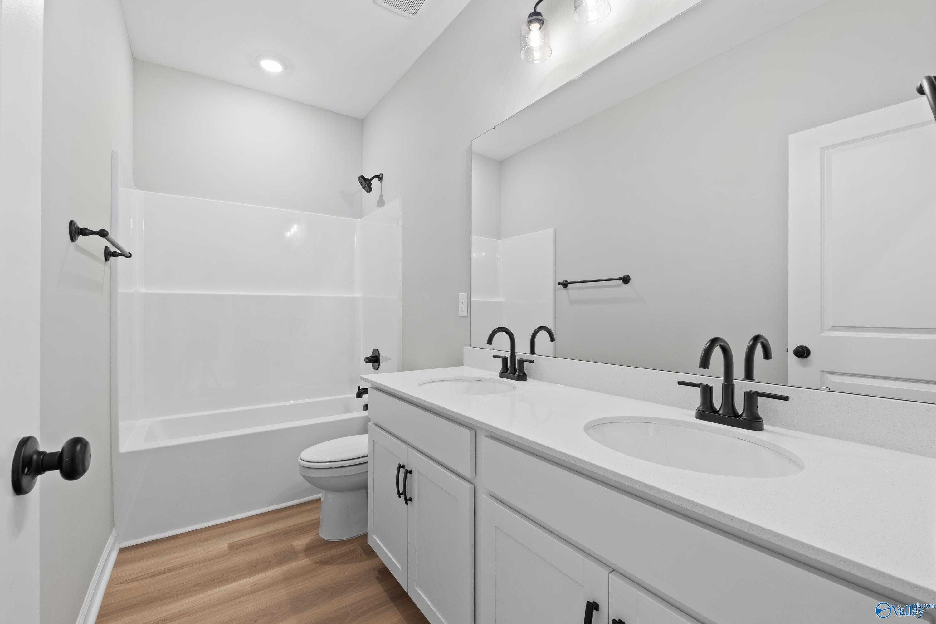 Bright modern bathroom with double vanity, white cabinets, bathtub, and walk-in shower in Davidson Homes The Phoenix, Hazel Green, AL