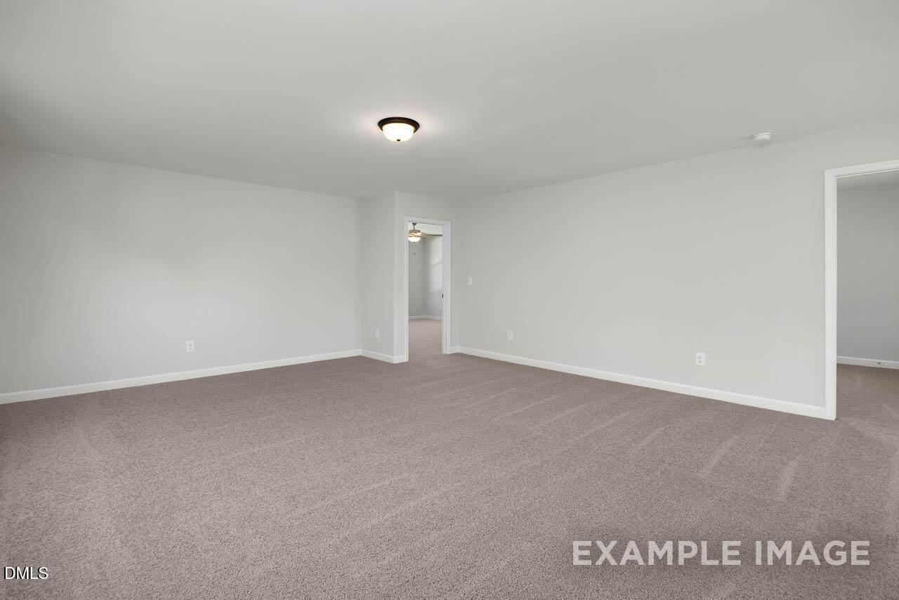 Spacious empty bedroom with light gray walls, beige carpet, and doorways in Davidson Homes Adalynn A, Lillington, NC