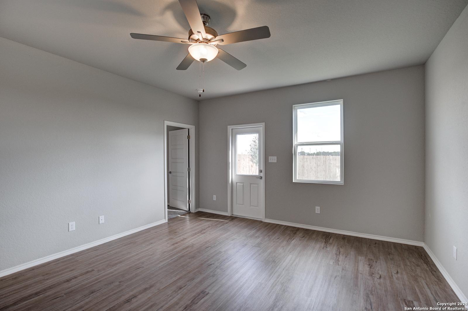 Bright master bedroom with gray walls, hardwood floors, ceiling fan, and patio access in Davidson Homes The Frio B, San Antonio