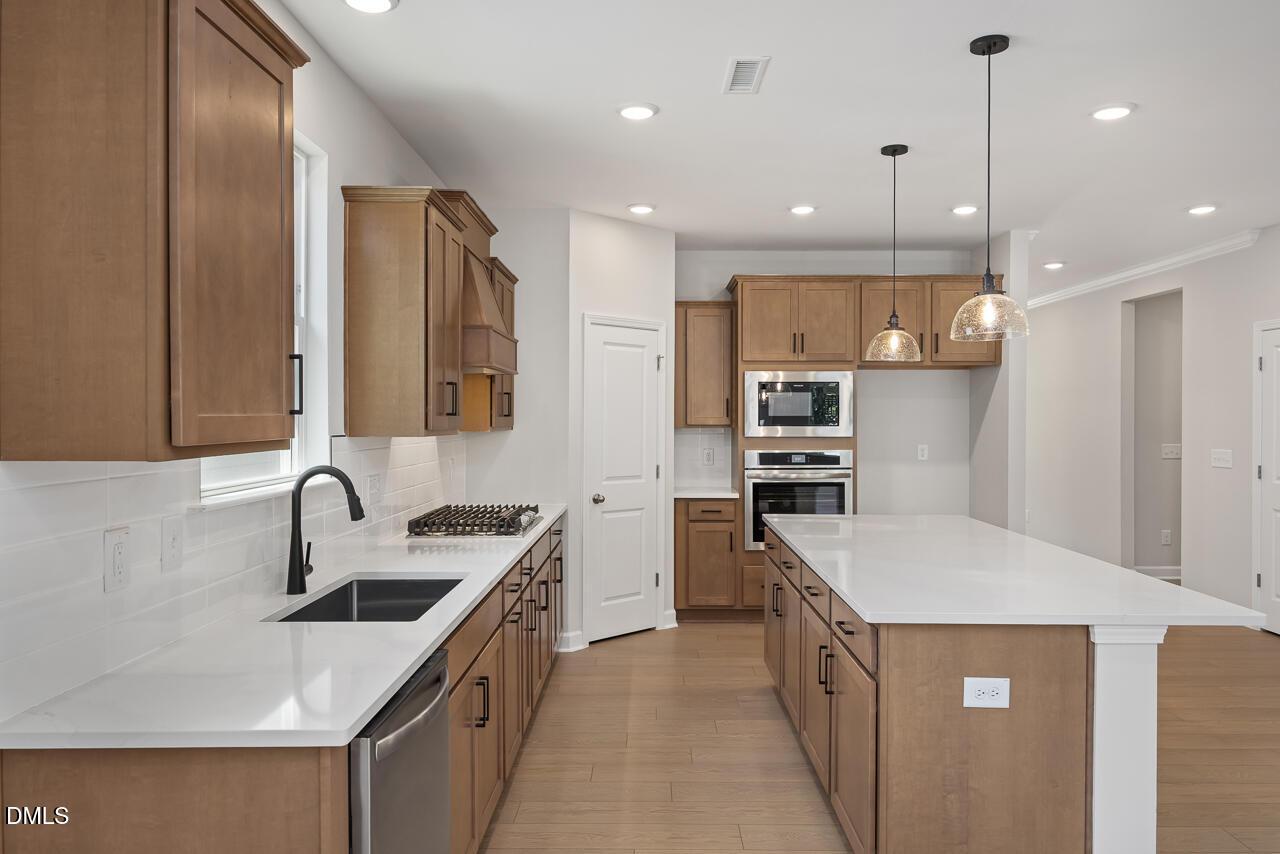 Modern kitchen with wood cabinets, quartz countertops, and large island in The Ashport L at Sage on North Main, Wake Forest.