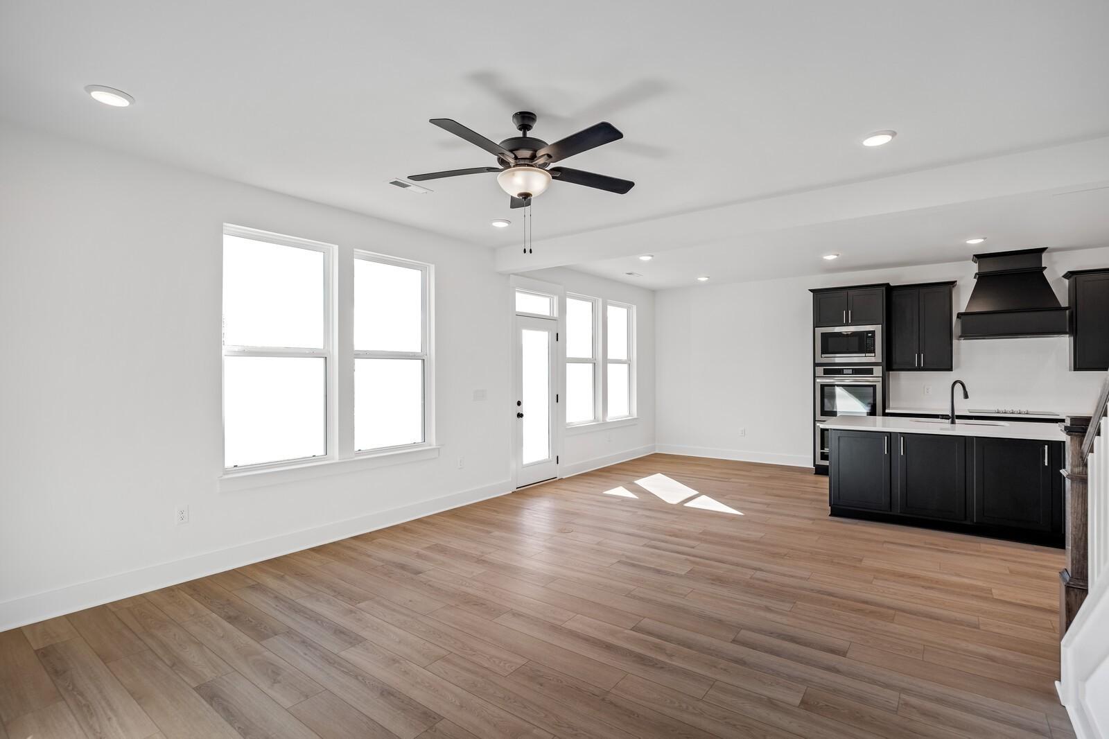 Bright open-concept kitchen with dark island cabinets, double ovens, and hardwood floors in Davidson Homes The Willow C, Gallatin, TN