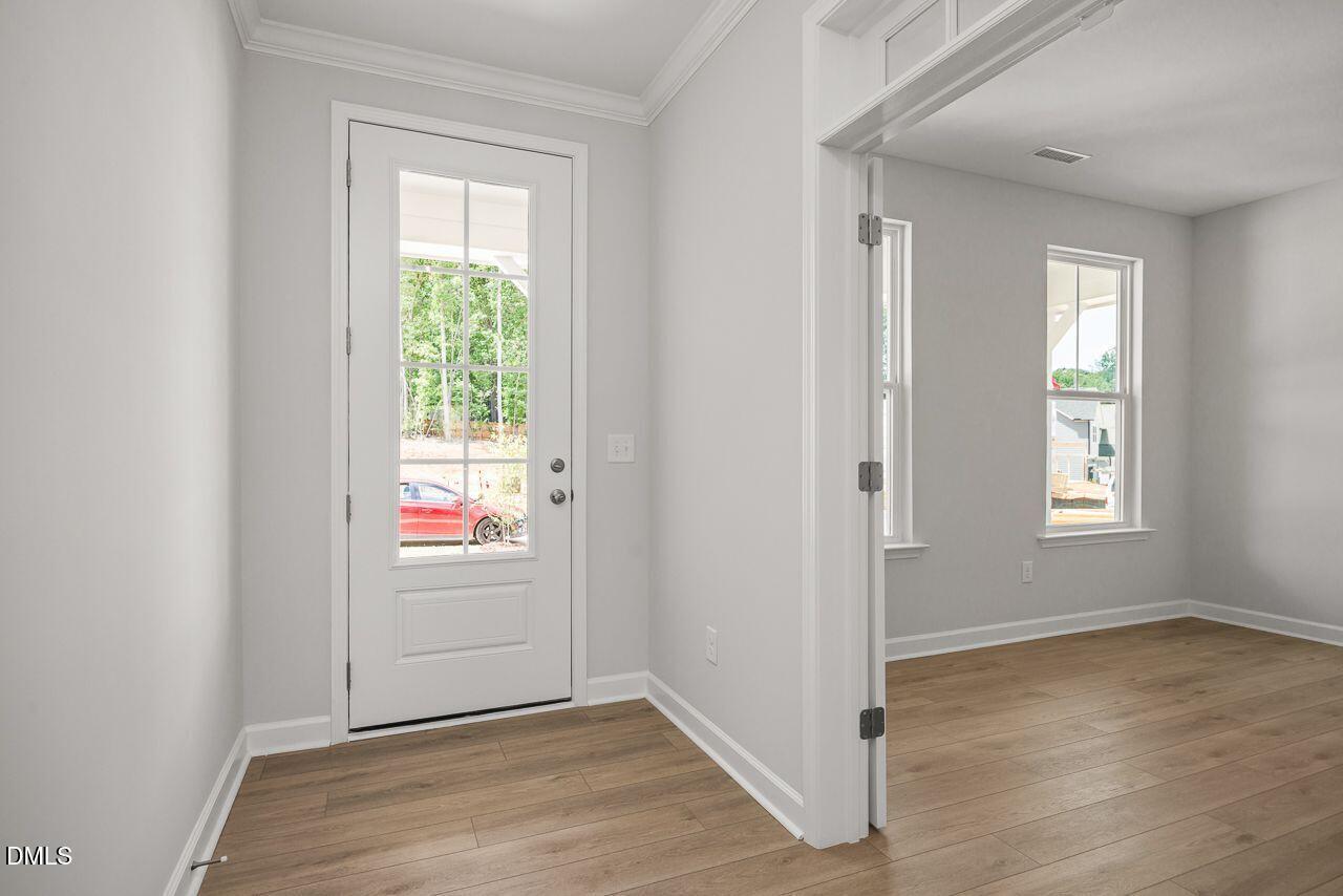 Bright entryway with wood-style flooring and glass-paneled door in The Birch II A floor plan at Montrose in Aberdeen, NC.