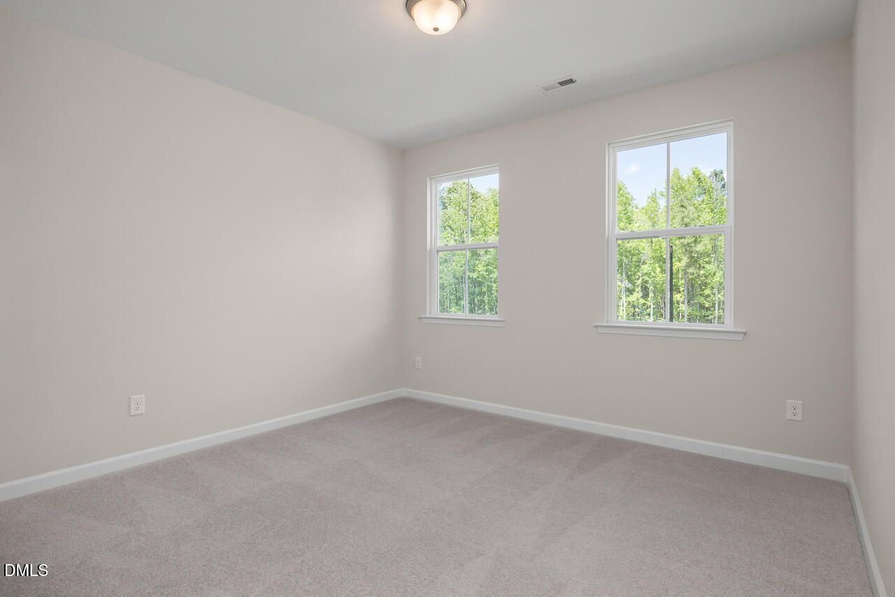 Spacious, carpeted bedroom with large windows in The Ashport G floor plan at Sage on North Main in Wake Forest, NC.