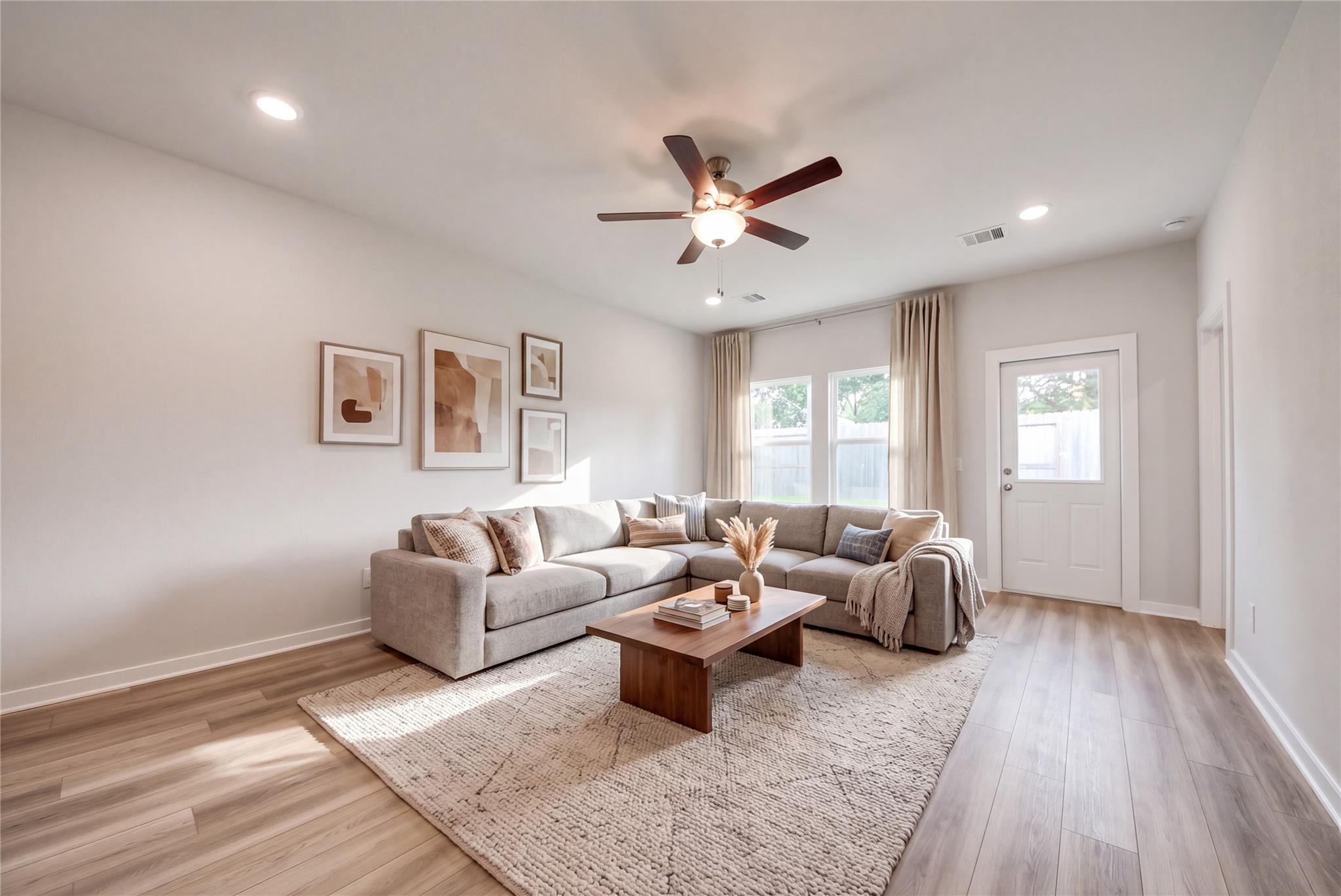 Bright, modern living room with gray sectional and wood coffee table in The Sabine E floor plan at Windmill Estates.