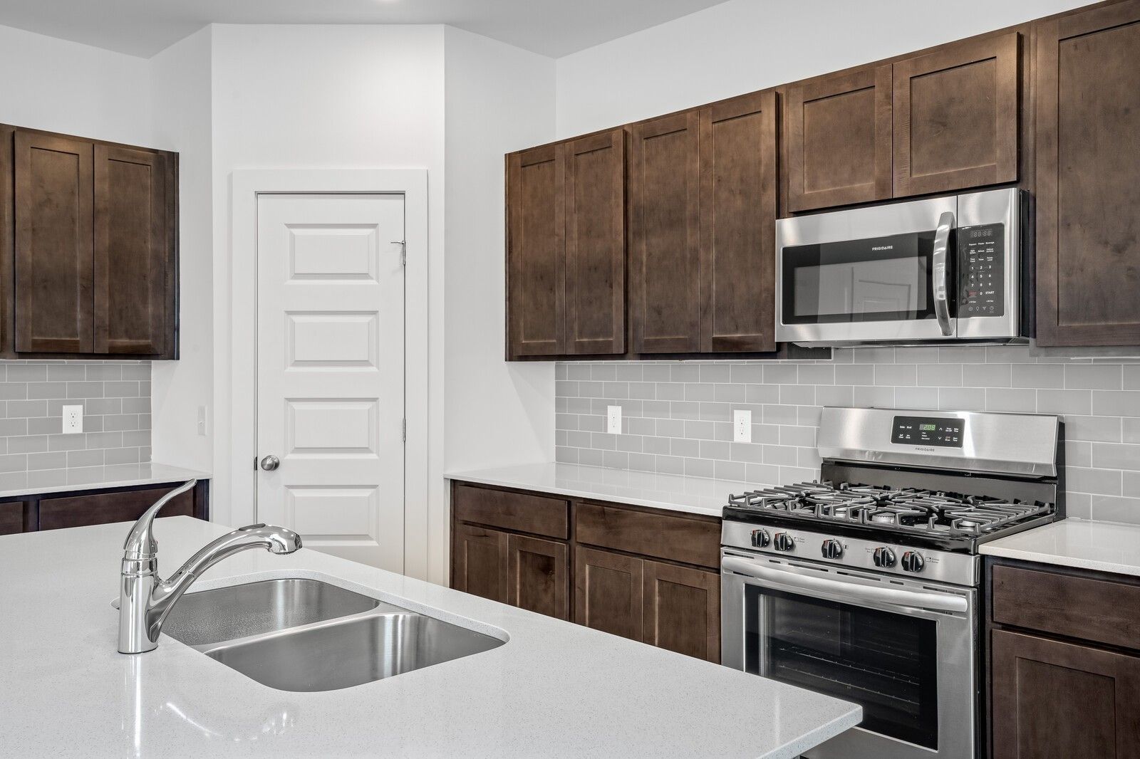Modern kitchen featuring shaker cabinets, stainless steel gas range, microwave, and subway tile backsplash in Davidson Homes The Logan C, White House, TN