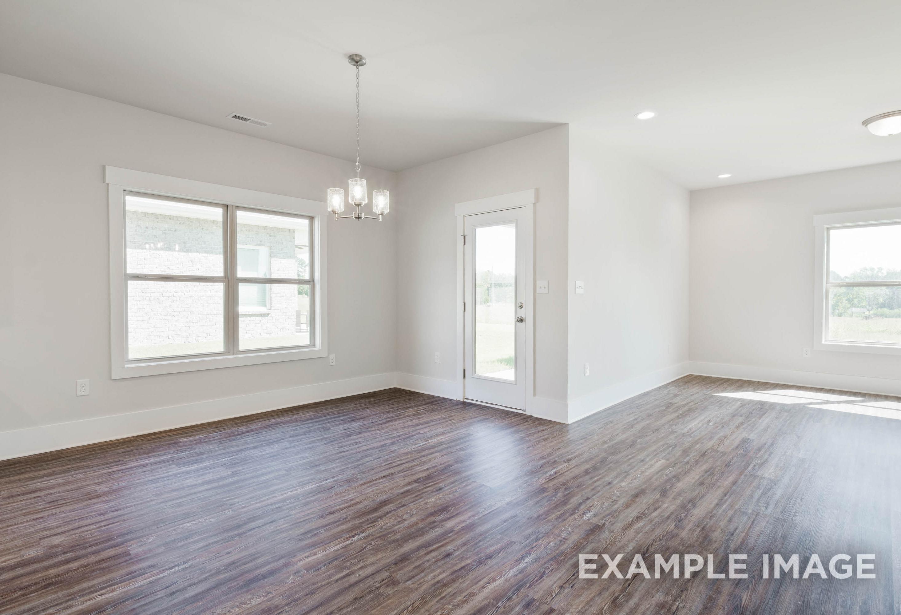 Bright dining area in The Richmond D featuring wood-style flooring, modern chandelier, and backyard access.