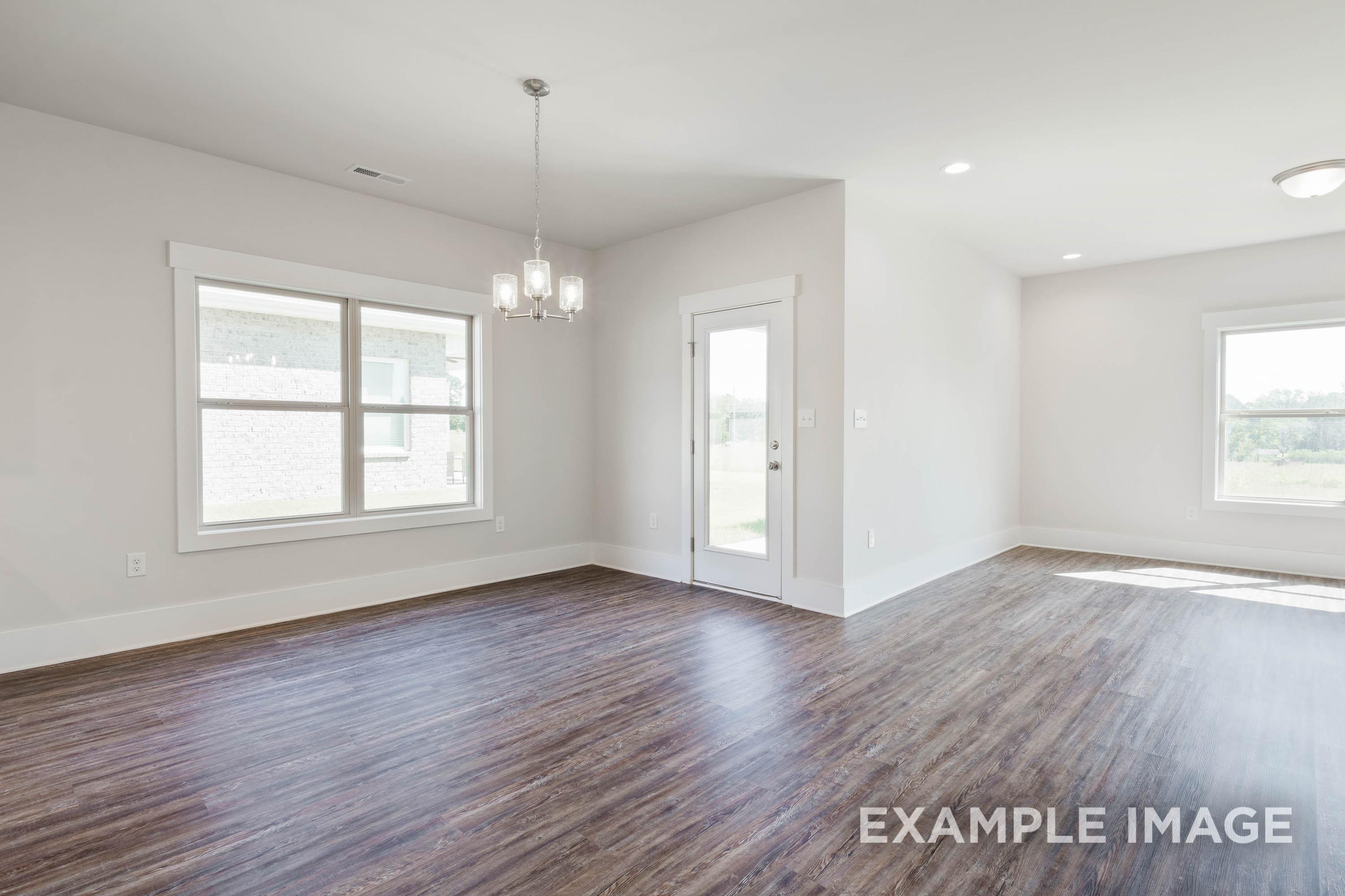 Bright dining area in The Richmond D featuring wood-style flooring, modern chandelier, and backyard access.