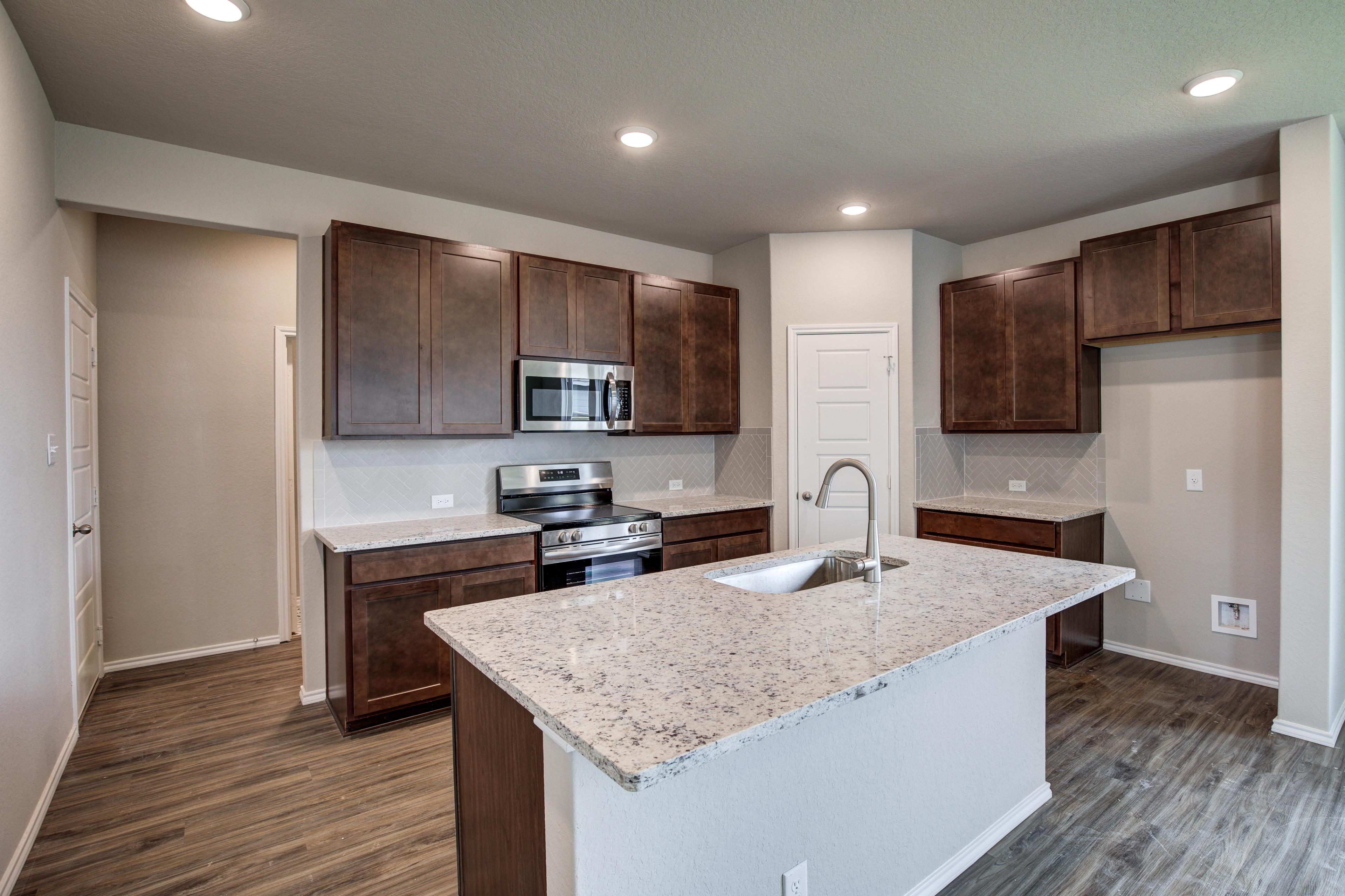 Gourmet kitchen in The Murray G Davidson Homes plan featuring quartz island, dark shaker cabinets, stainless appliances