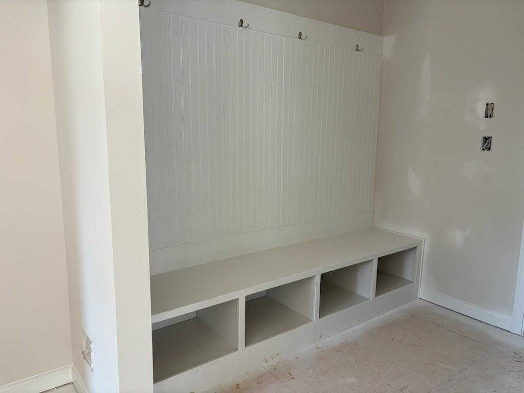 Custom white mudroom with built-in lockers, coat hooks, and bench seating in Davidson Homes The Hickory A, Riverwood, Dallas, Georgia