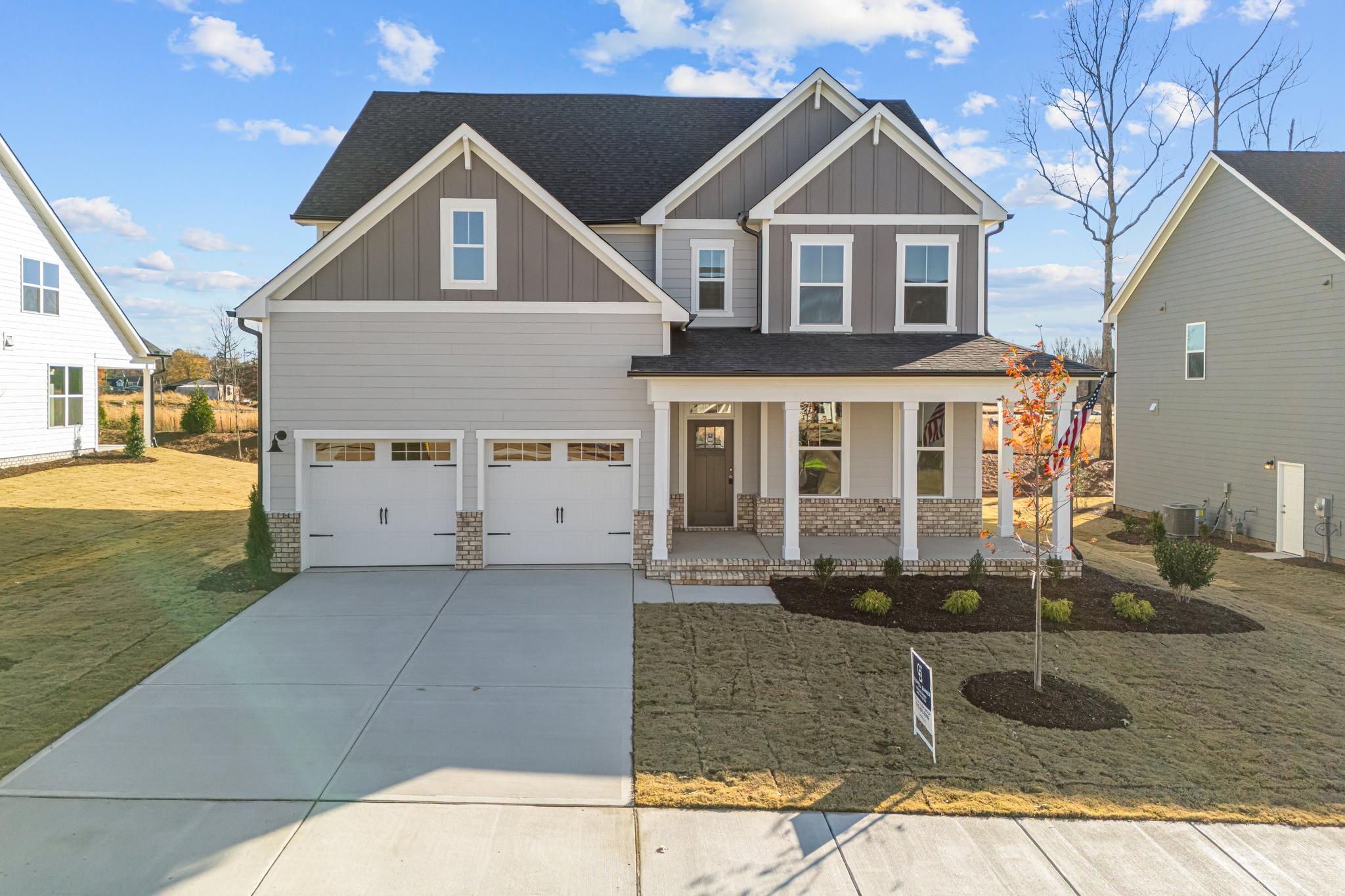 Modern two-story gray home exterior at Enclave at Belmont in Belmont NC with covered front porch, two-car garage and landscaped yard