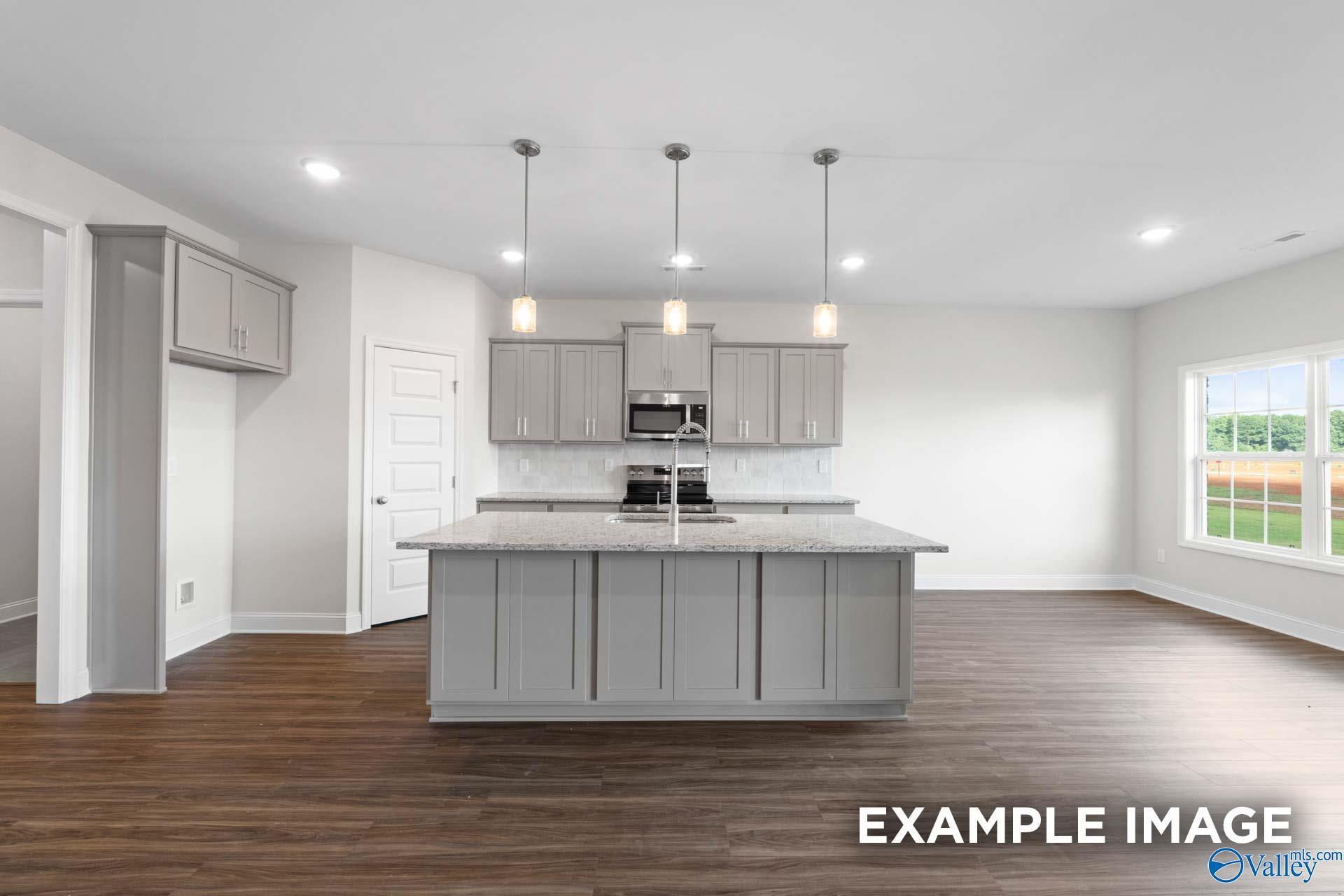 Modern open-concept kitchen with gray island, stainless appliances, white counters in Davidson Homes The Montgomery, Hartselle, AL