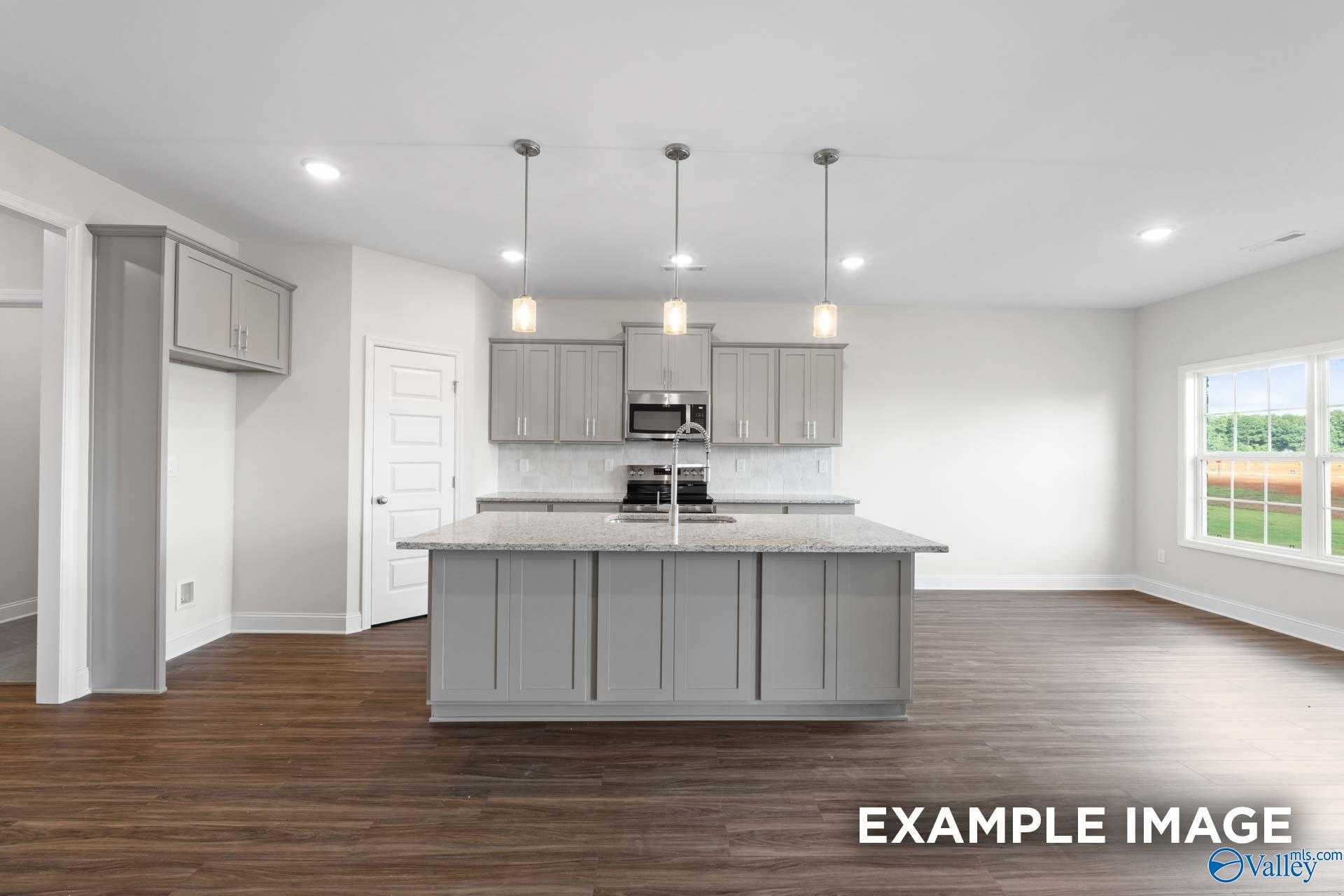 Modern gray kitchen island with sink, stainless appliances, pendant lights in Davidson Homes The Montgomery, Hartselle, Alabama