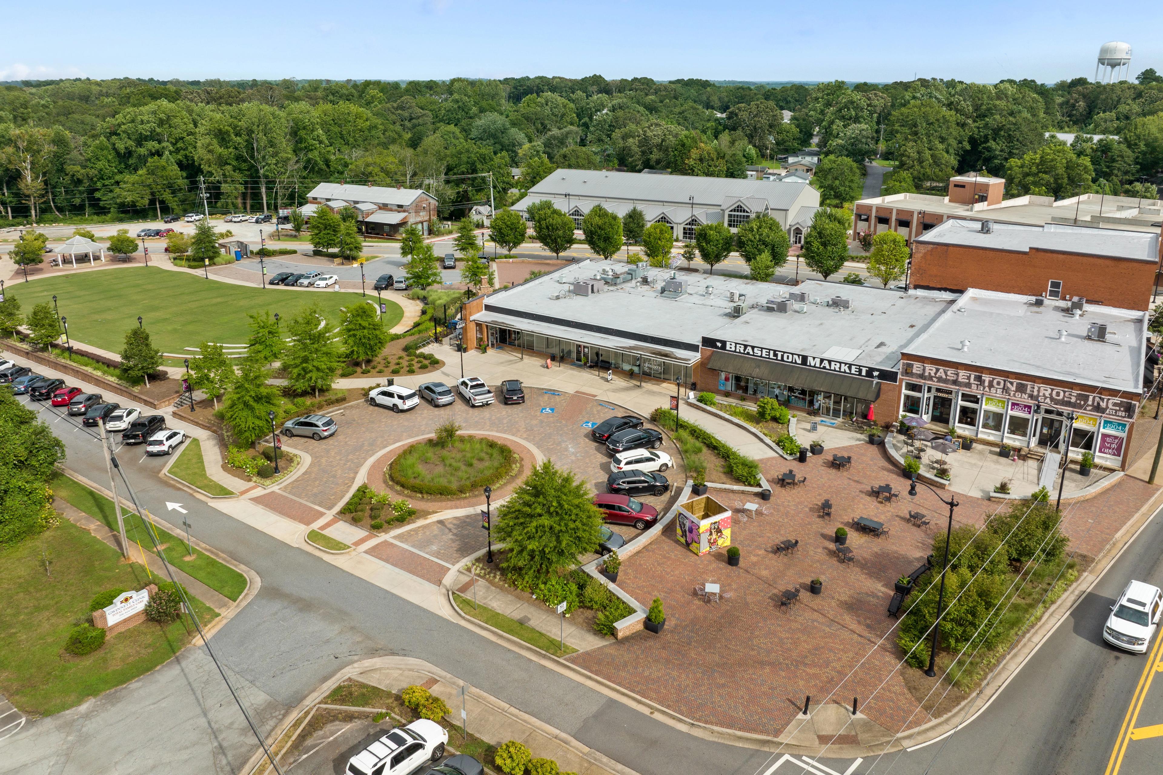 Aerial view of Charleston Market and brick storefronts at Wehunt Meadows in Hoschton Georgia with parking lots and tree-lined paths