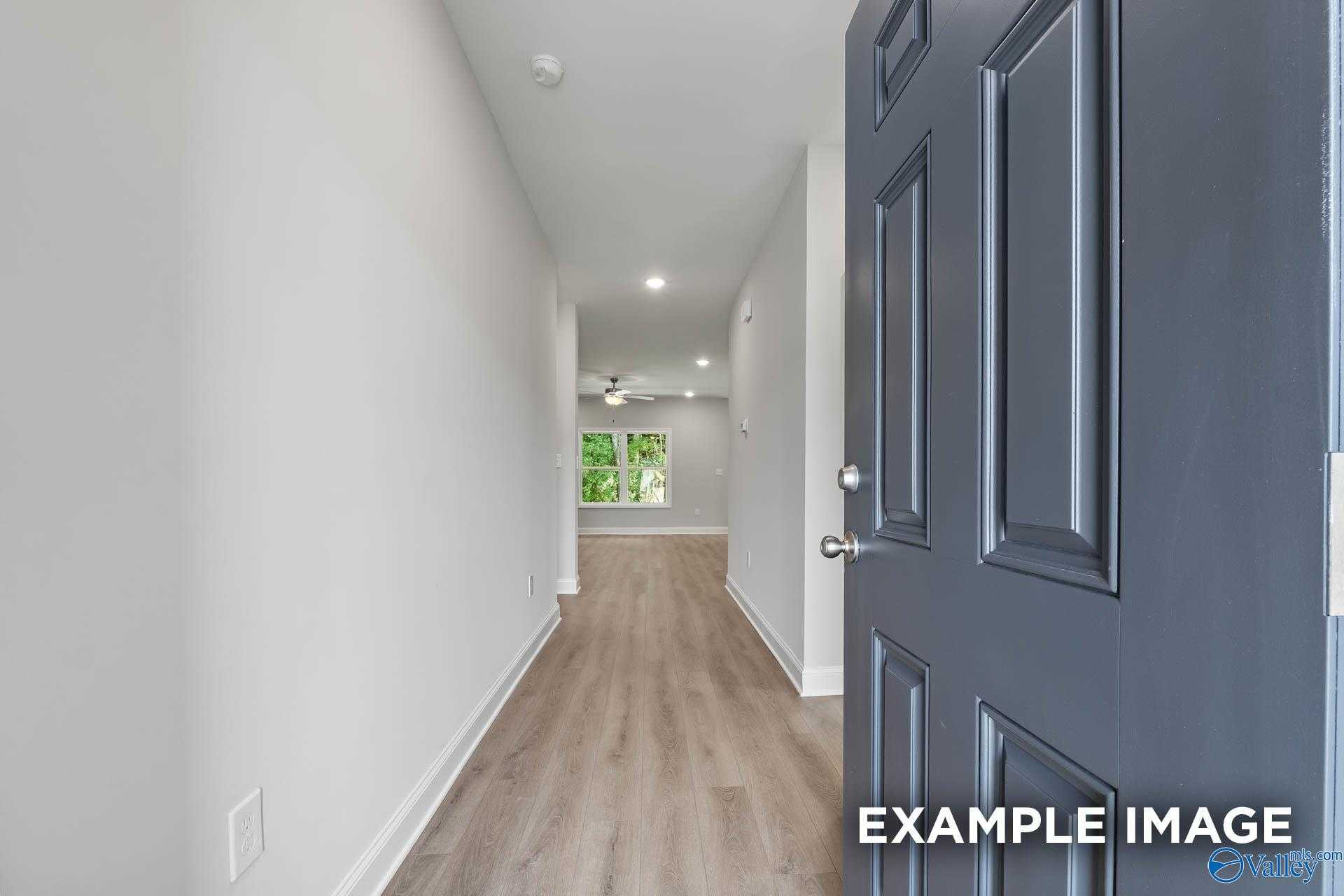 Bright entry hallway with luxury vinyl plank flooring, white walls, and open living space in The Asheville C by Davidson Homes, Huntsville AL
