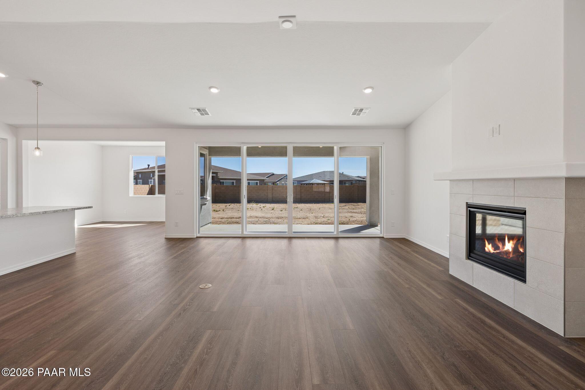 Spacious great room with gas fireplace, hardwood floors, and desert mountain views through sliding doors in The Monarch A, Prescott, AZ
