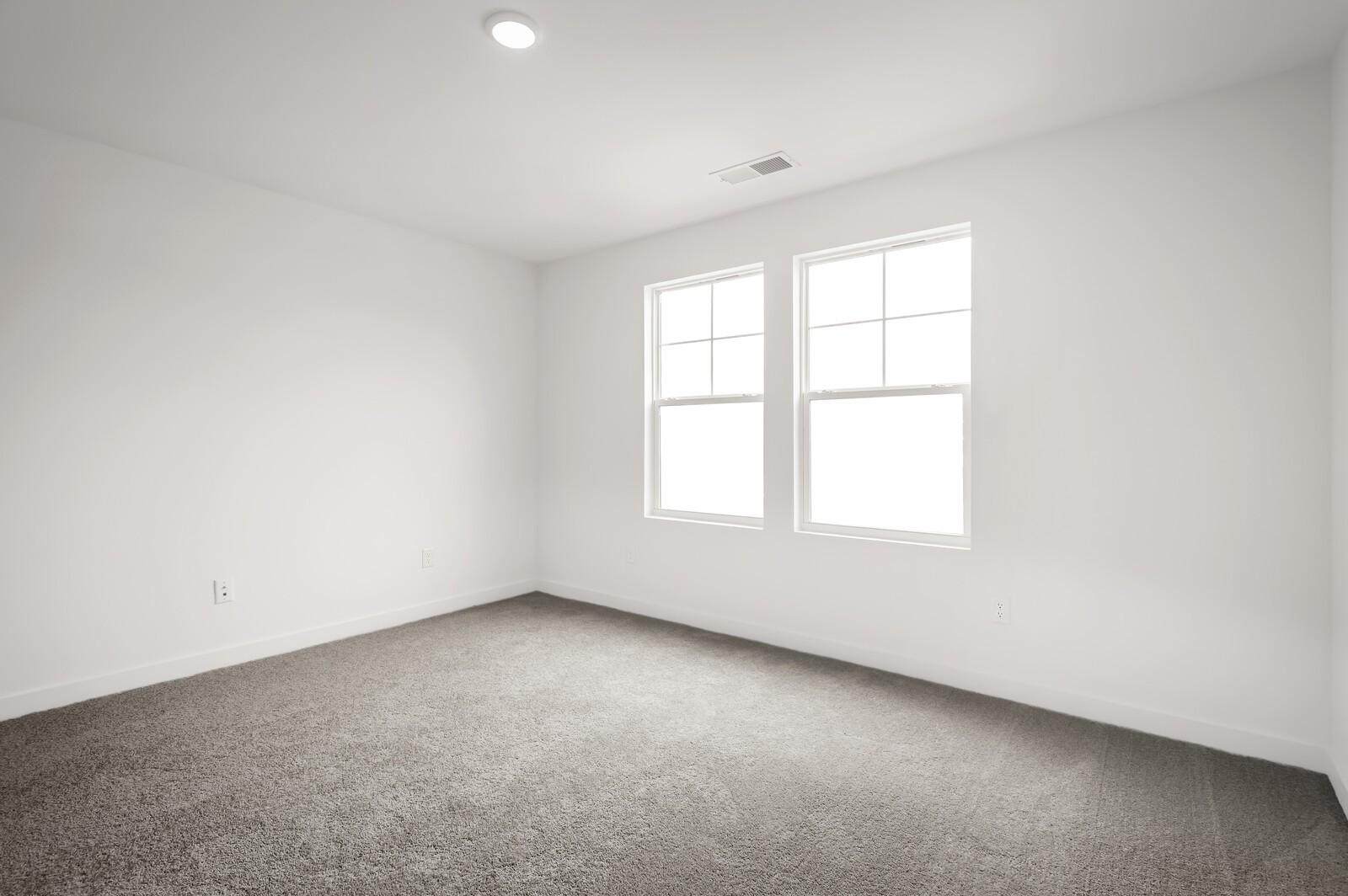 Bright, carpeted bedroom with white walls and natural light in The Logan C floor plan at Calista Farms, White House, TN.