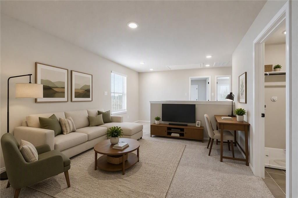Bright neutral living room with sectional sofa, round wood coffee table, and TV wall in Davidson Homes Charlotte B plan, Cartersville, GA