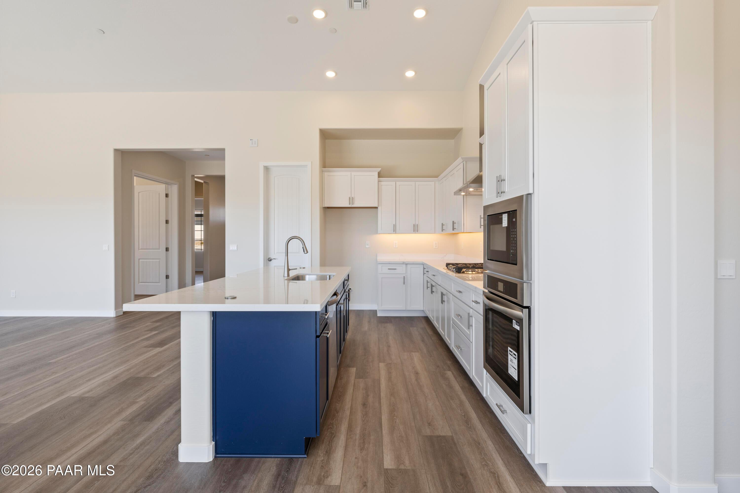 Modern open-concept kitchen with white cabinets, blue island, quartz counters, stainless appliances in Davidson Homes Soleil E, Prescott AZ