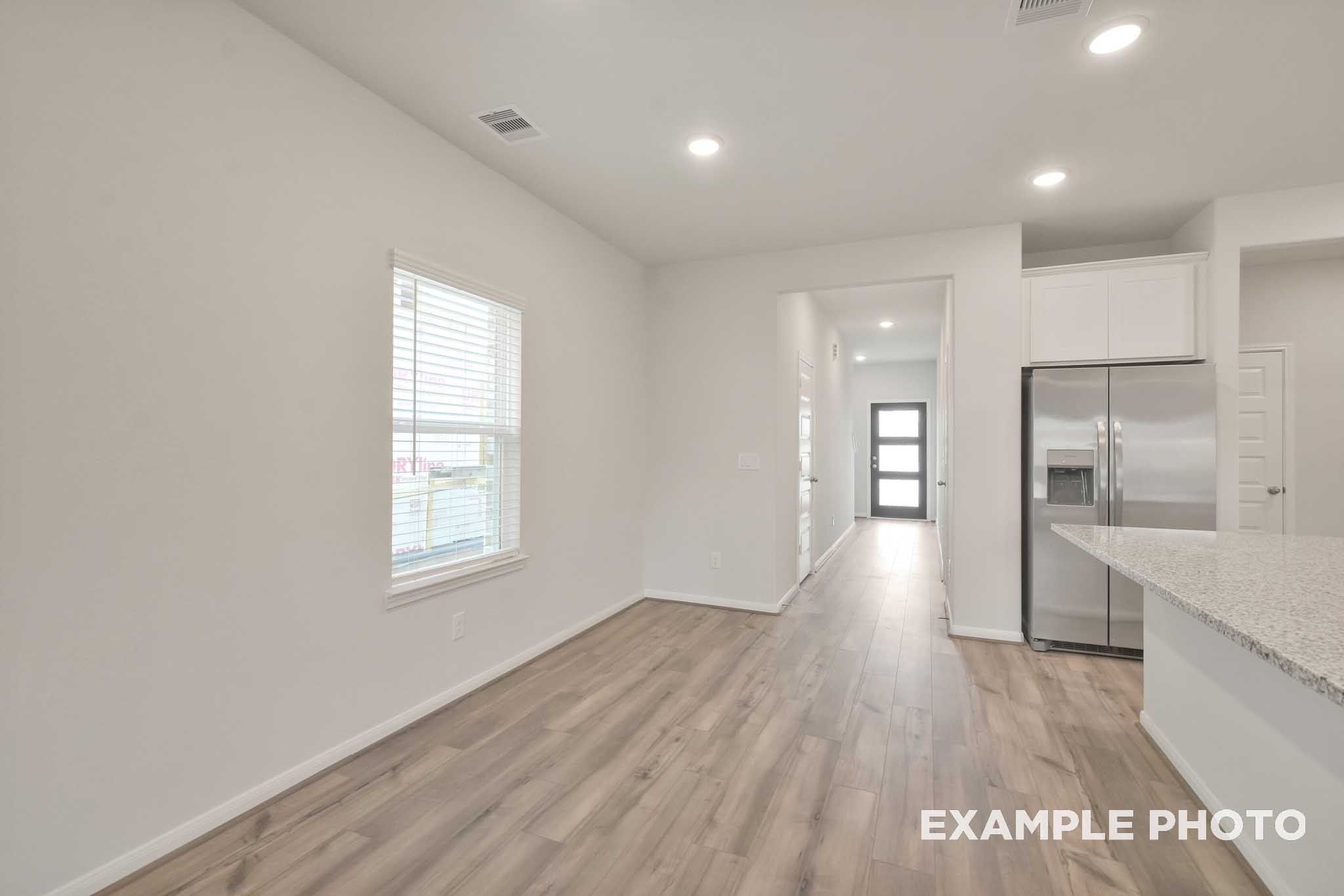 Bright open-concept interior of The Brazos by Davidson Homes featuring wood-look flooring, granite counters, and stainless appliances
