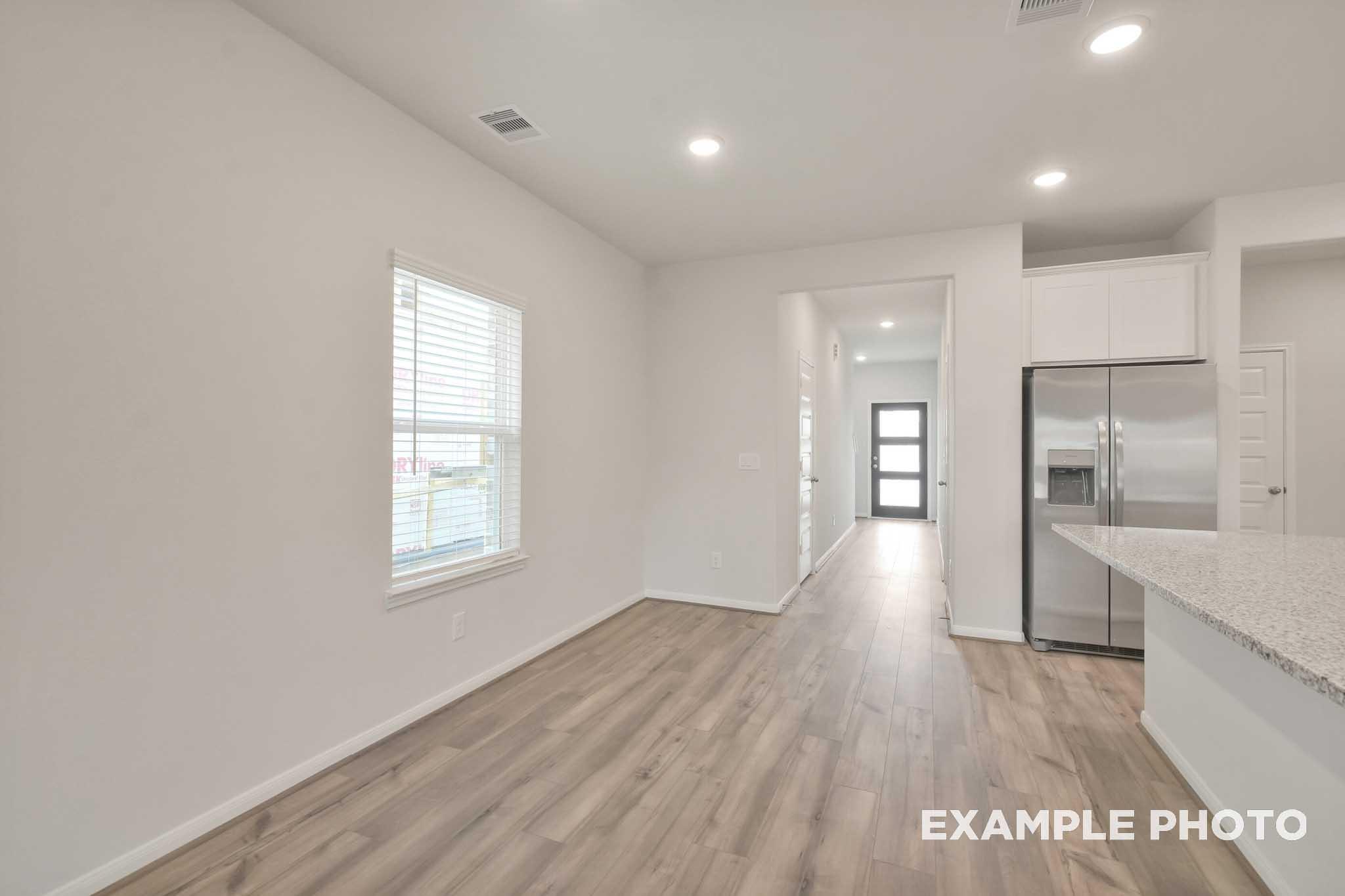Bright open-concept interior of The Brazos by Davidson Homes featuring wood-look flooring, granite counters, and stainless appliances