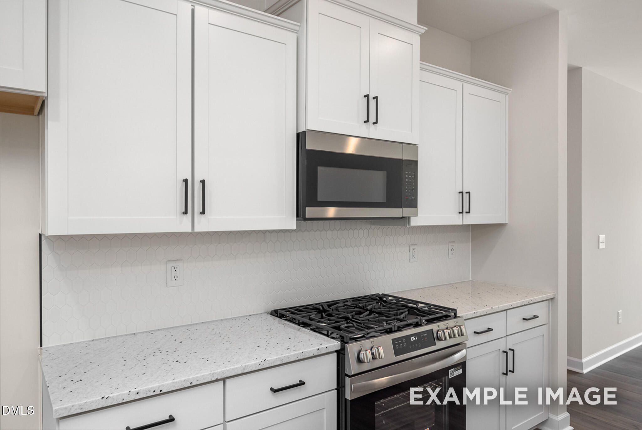Modern kitchen with white shaker cabinets, granite countertops, and stainless steel appliances in The Mitchell floor plan.