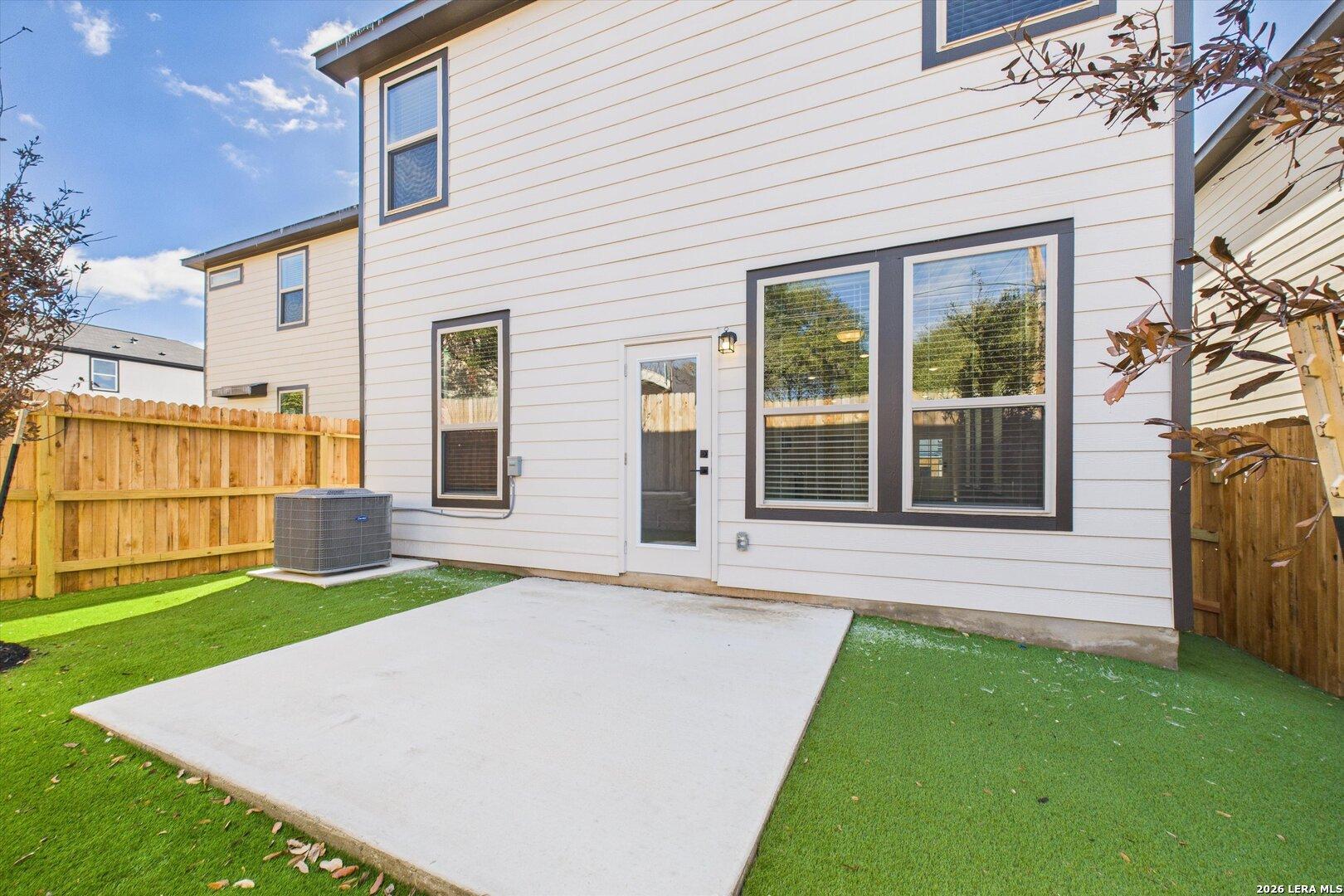 Spacious backyard patio with glass door access and green turf lawn in The Gillian B 4-bedroom home, Meadows at Oak Creek, San Antonio, Texas