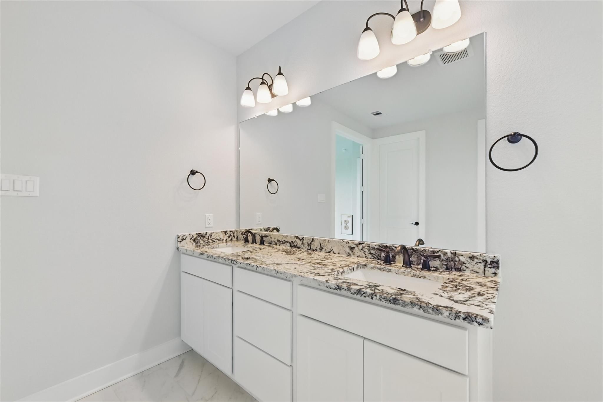 Modern double vanity with quartz countertop and white cabinets in master bath of Davidson Homes The Victoria C, Texas City