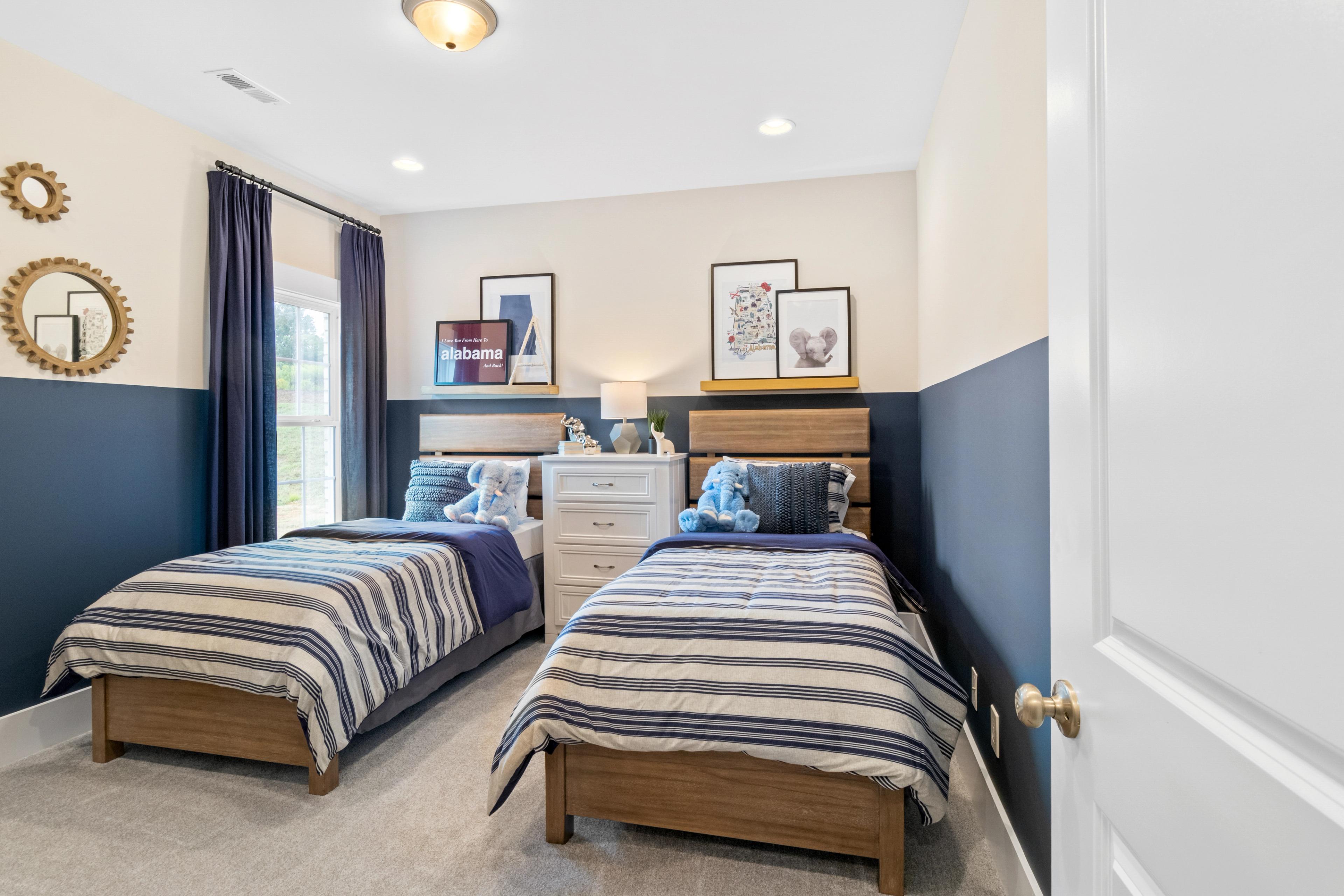 Cozy kids' bedroom with twin beds, navy accent wall, striped bedding and teddy bears in Noble Ridge, Cullman Alabama by Davidson Homes