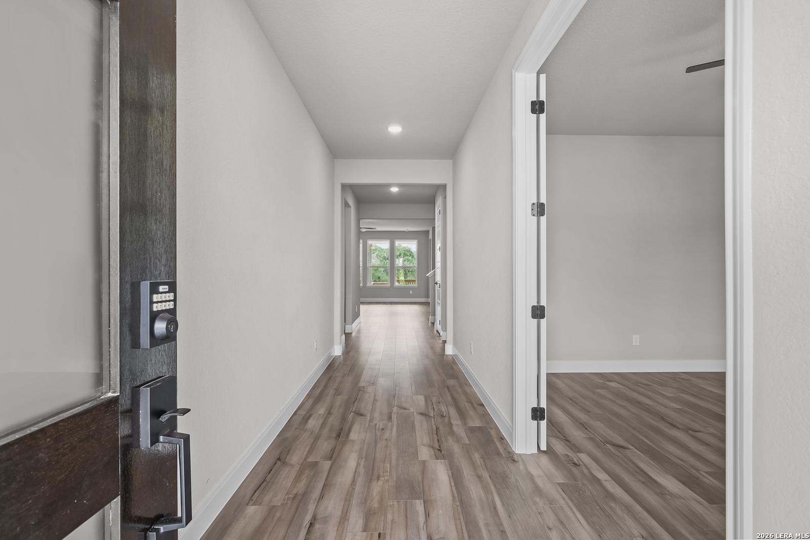 Elegant entry hallway with light wood floors, gray walls, and keypad lock in Davidson Homes The Belmont H, Castroville, Texas