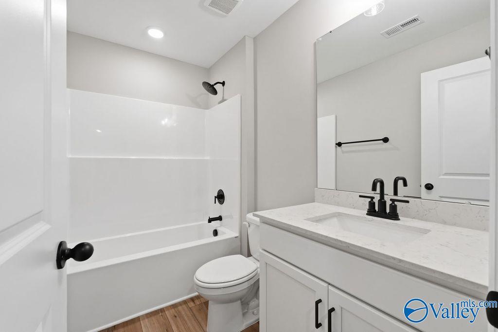 Modern bathroom with white vanity, quartz countertop, and tub-shower combo in The Rockford home at Cain Park, Hartselle.