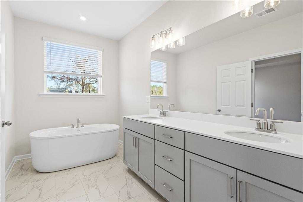 Elegant master bathroom featuring freestanding tub, double vanity with gray cabinets in Davidson Homes The Glenwood C at Wehunt Meadows, Hoschton