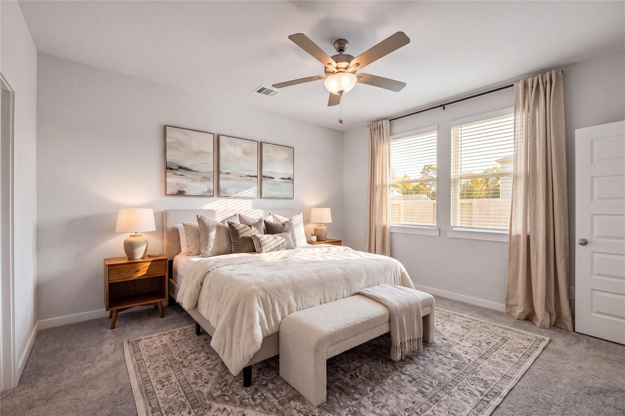 Bright primary bedroom with ceiling fan, large windows, and neutral decor in Davidson Homes The Brazos F, Cleveland, Texas