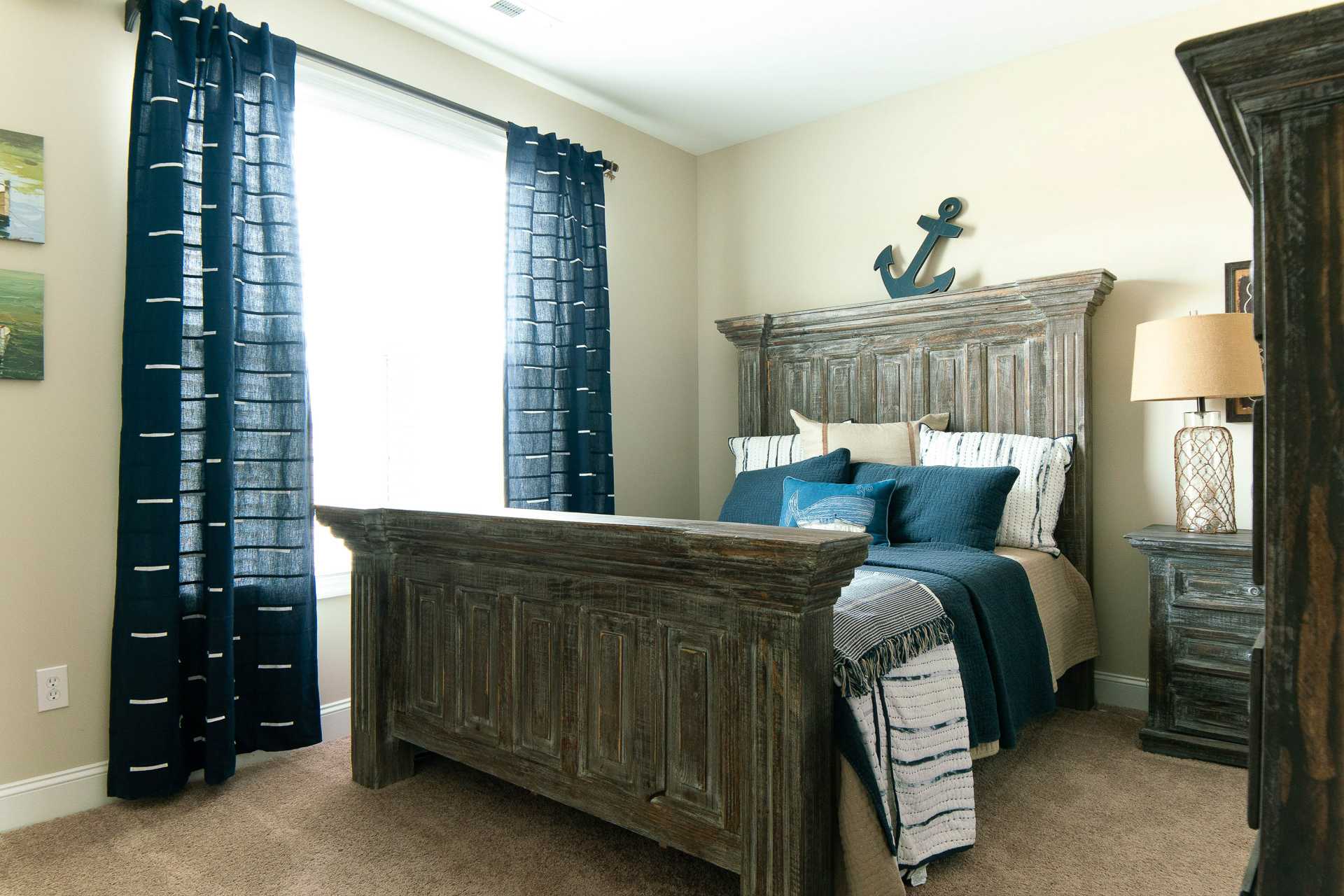Cozy bedroom at The Dairy at Oak Grove in South Huntsville AL with rustic wooden bed, navy bedding, curtains, and anchor decor