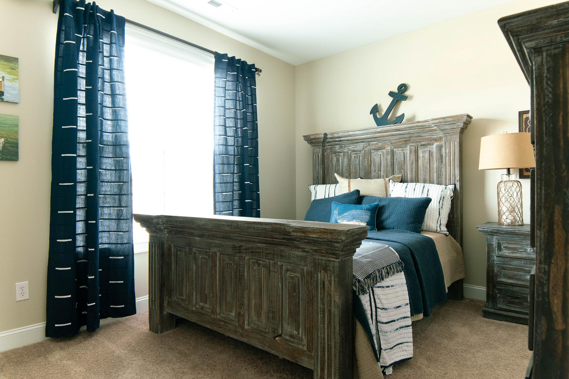 Cozy bedroom at The Dairy at Oak Grove in South Huntsville AL with rustic wooden bed, navy bedding, curtains, and anchor decor