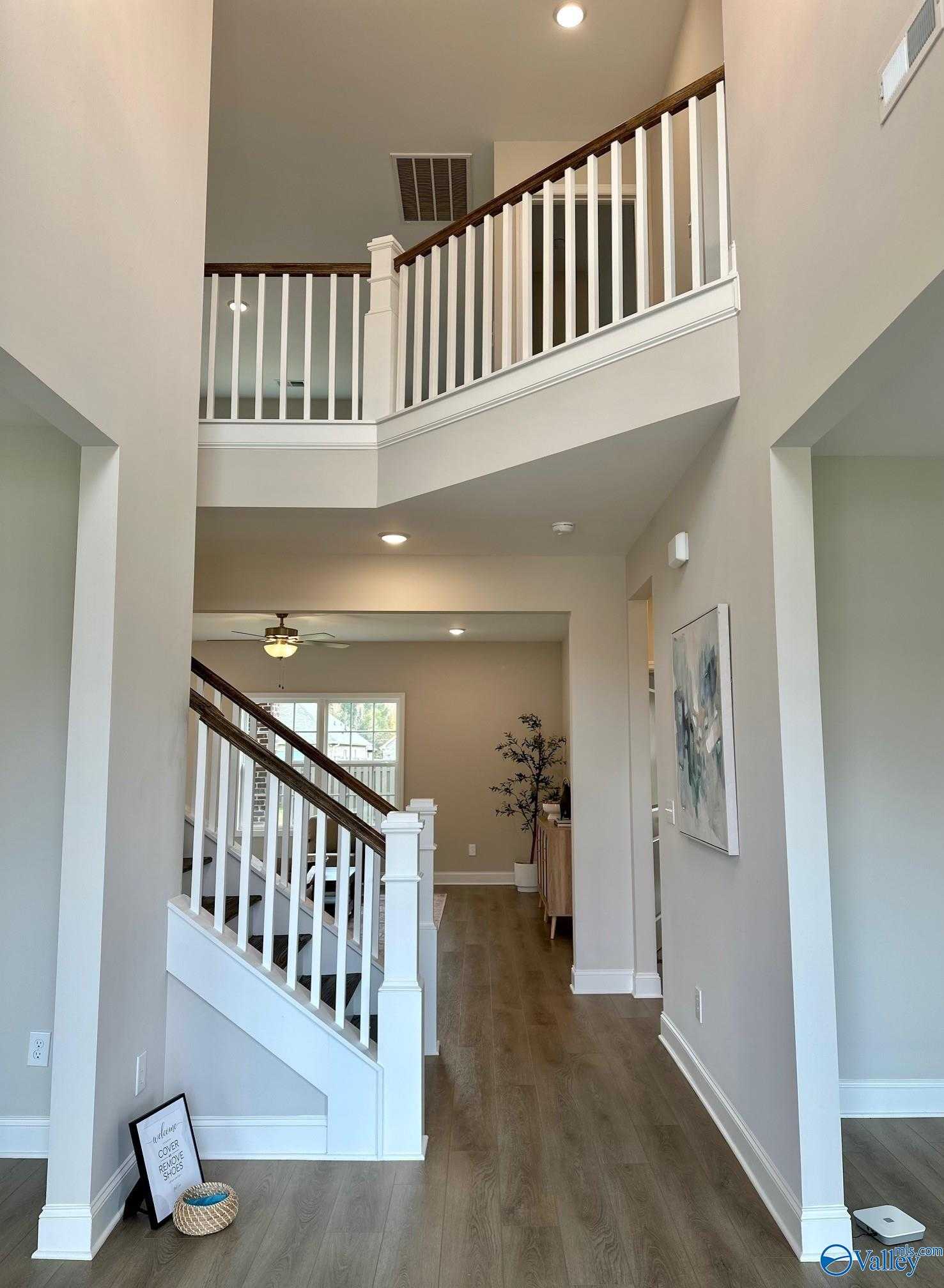 Elegant two-story foyer with grand white-railed staircase and hardwood floors in Davidson Homes The Madison A, Toney, Alabama
