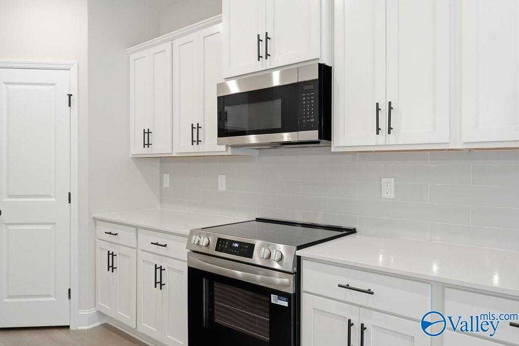 Modern white kitchen with stainless steel appliances, subway tile backsplash, and quartz counters in Davidson Homes The Rockford B, Hartselle, AL