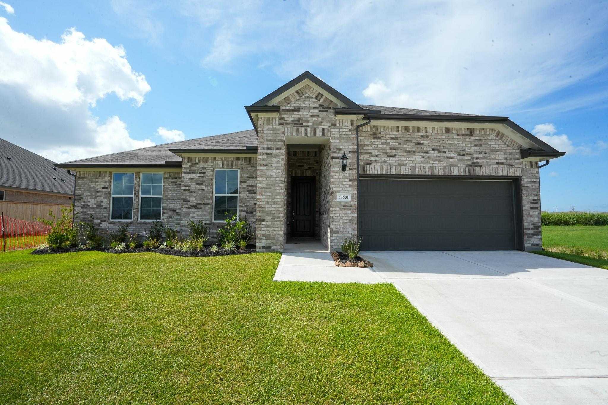Modern 1-story brick home with stone accents, 2-car garage, and lush front yard in Lago Mar, Texas City - Davidson Homes Edward A