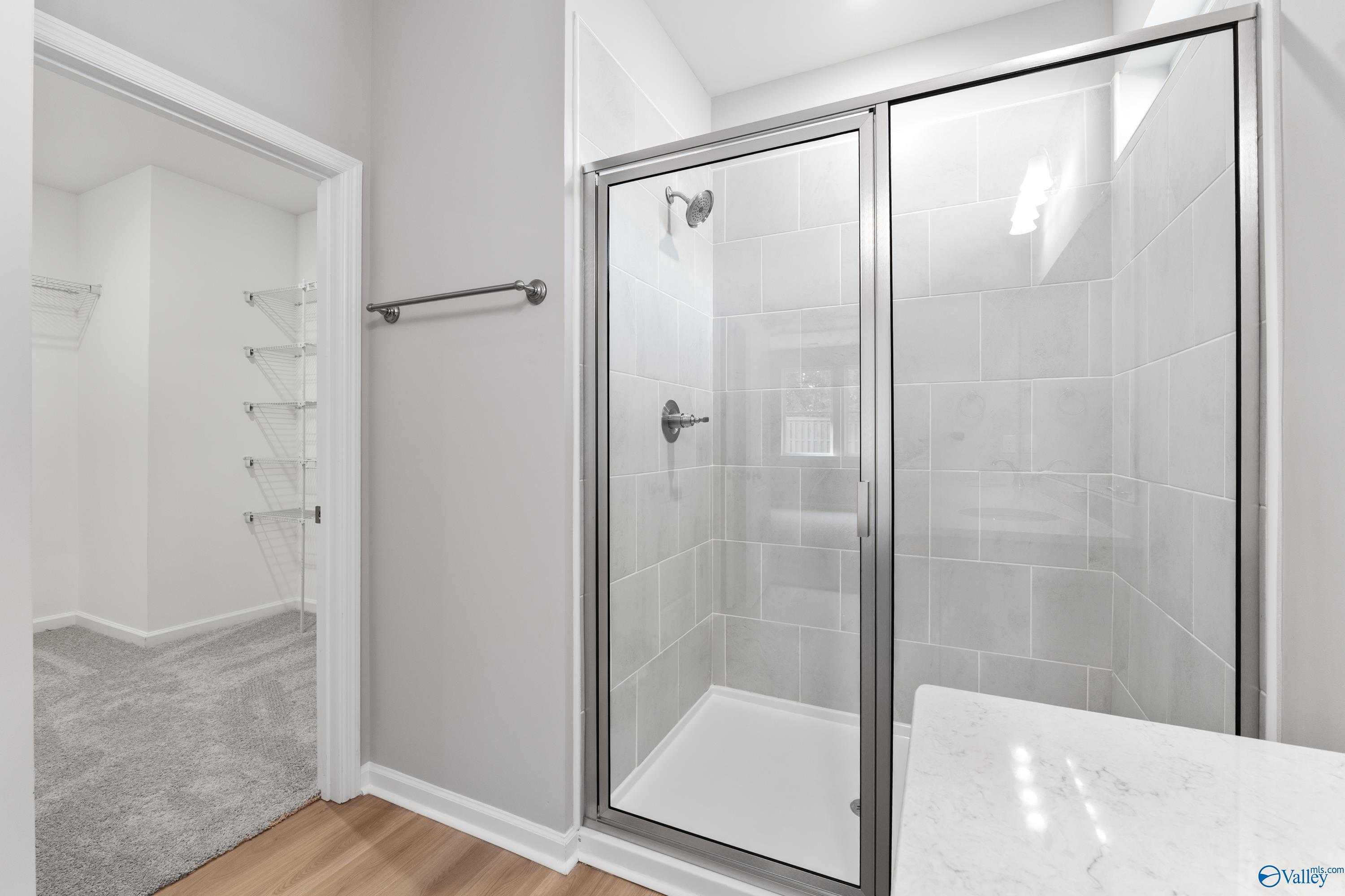 Modern master bathroom featuring frameless glass walk-in shower, subway tile, and marble vanity in The Grace, Evermore Homes, Madison, AL