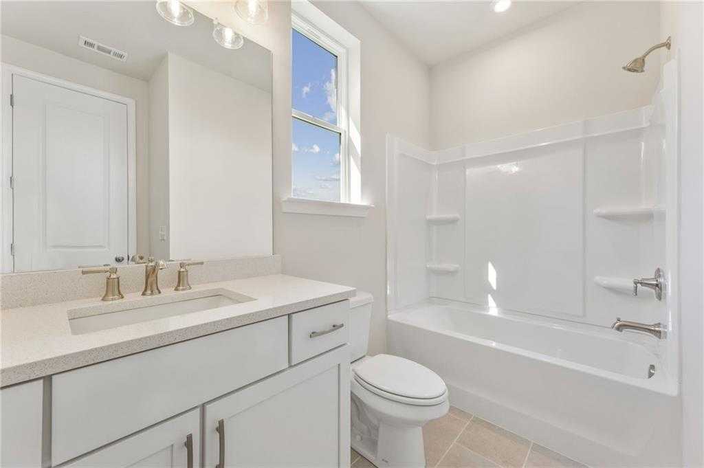 Modern bathroom with white subway tile shower, soaking tub, quartz vanity, bronze fixtures in Davidson Homes The Danbury E, Buford, GA