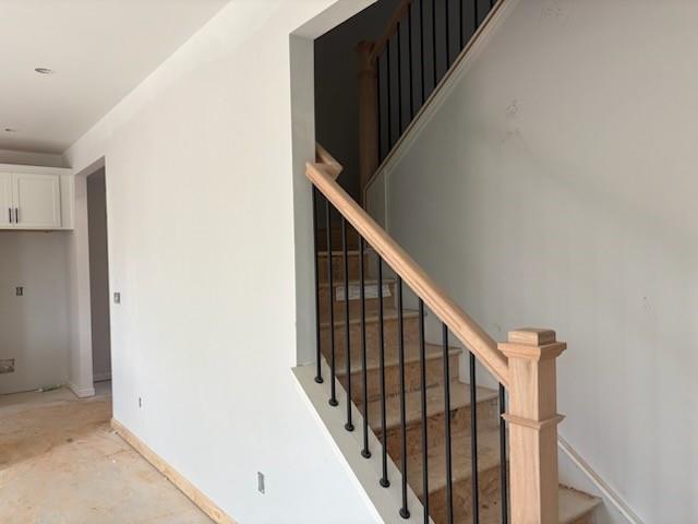Grand oak staircase with black metal balusters and white walls in 5-bedroom The Hickory B home, Winder, Georgia