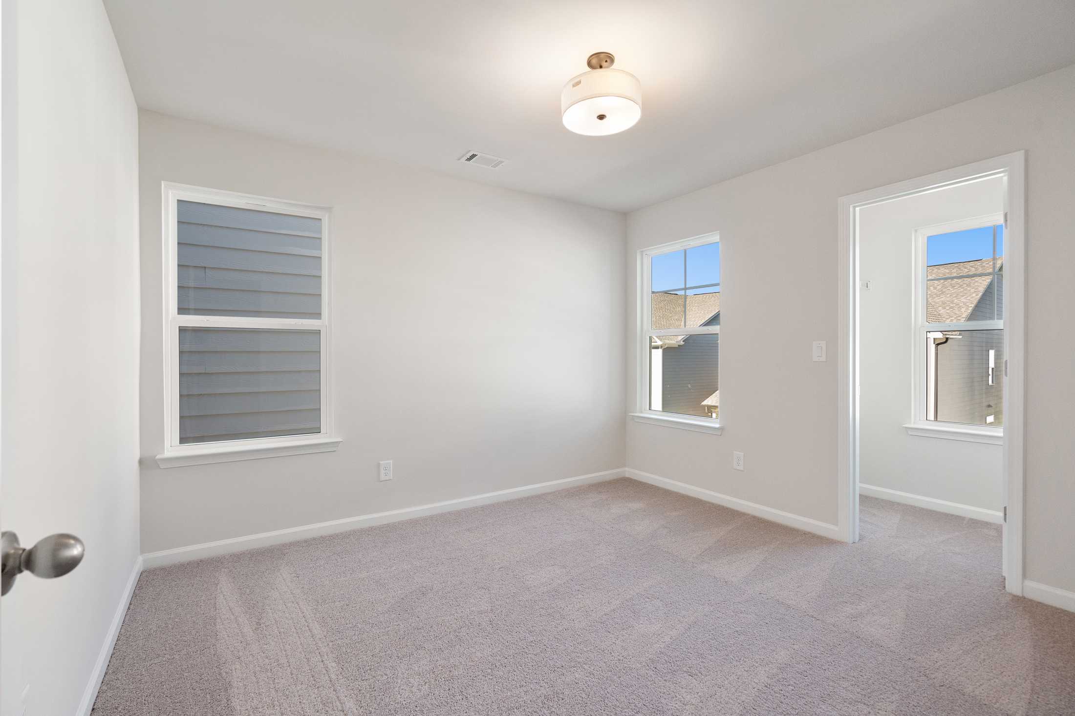 Spacious secondary bedroom in The Cary B with neutral walls, carpeted floors, large windows, and ceiling fixture