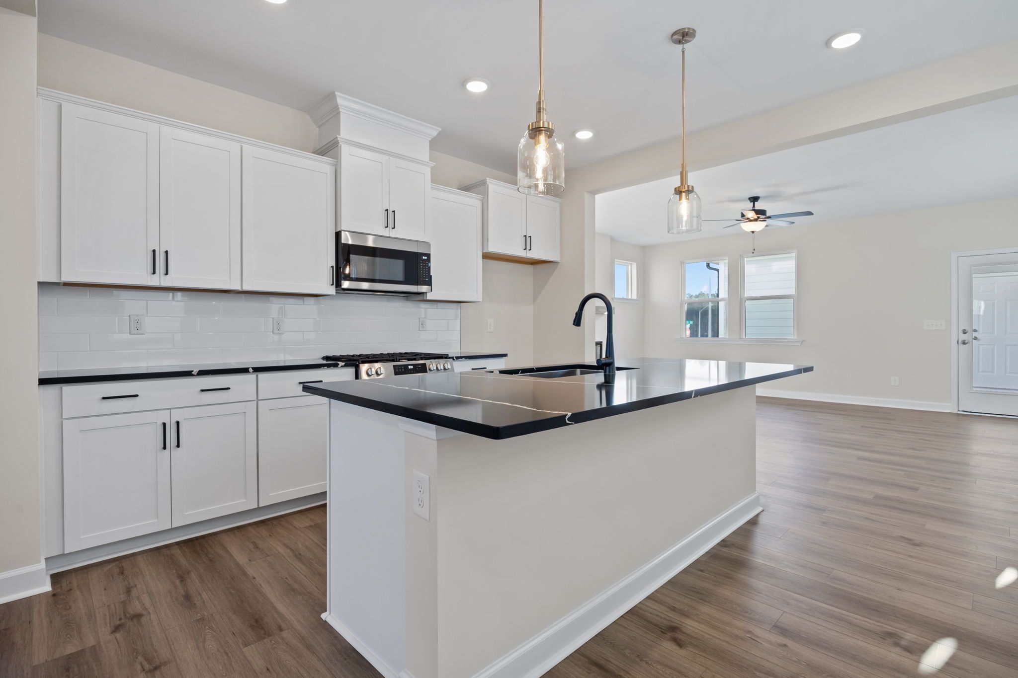 Modern kitchen at Forestville Yard in Knightdale, NC by Davidson Homes with white cabinets and black quartz island.