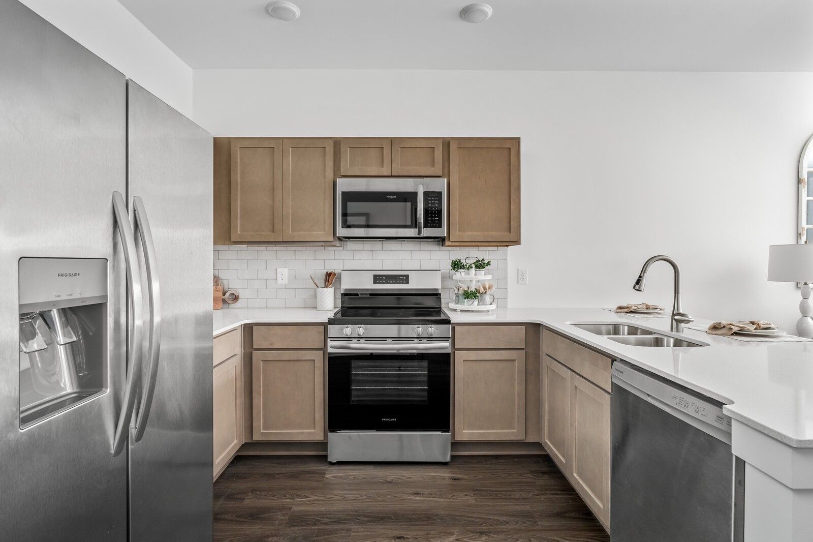 Open-concept kitchen with stainless steel appliances, white quartz counters, and beige shaker cabinets in Davidson Homes Cumberland A, Gallatin, TN