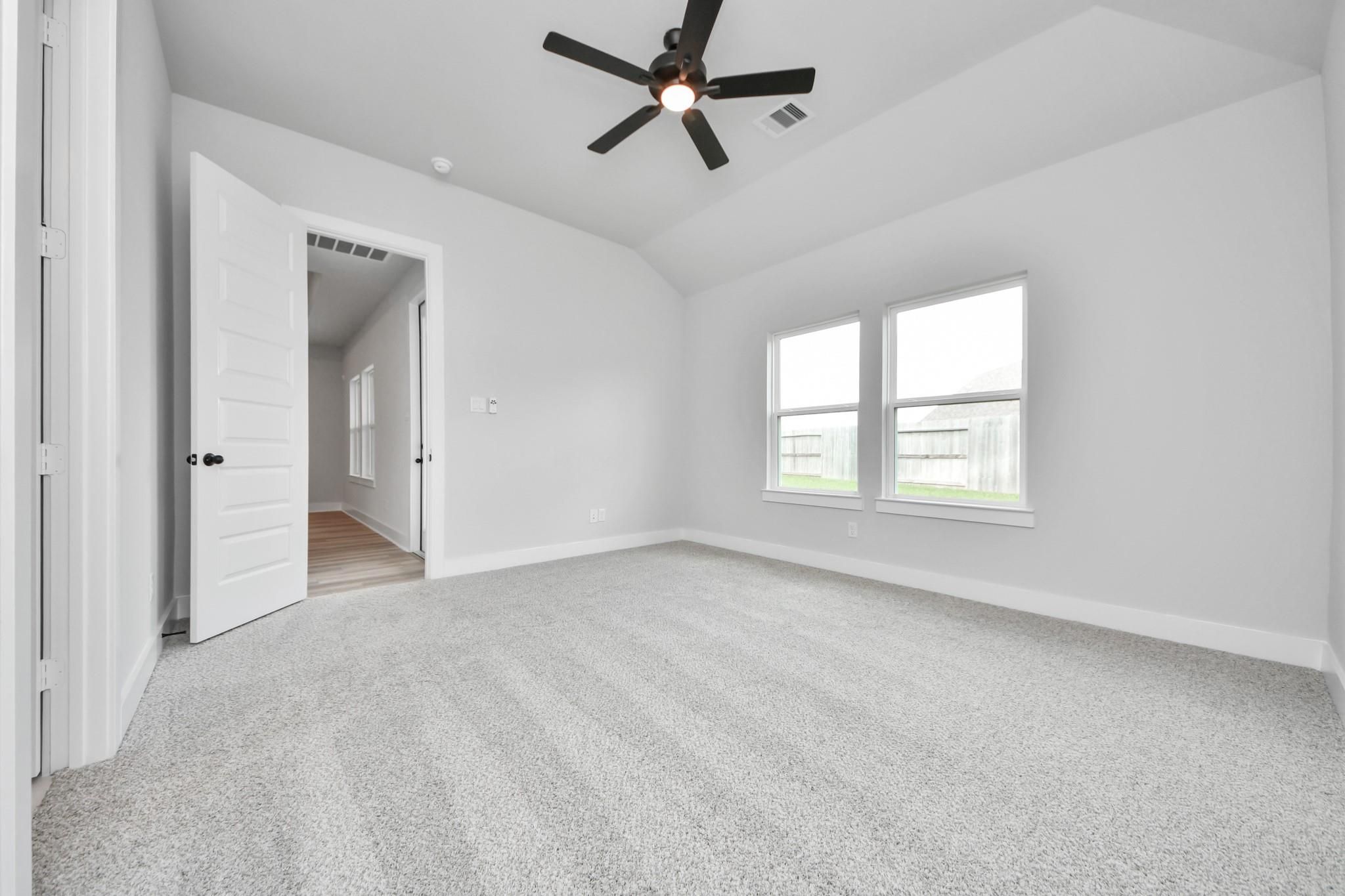 Bright, carpeted bedroom with ceiling fan in The Laguna C floor plan by Davidson Homes in Sunterra, Katy, Texas.